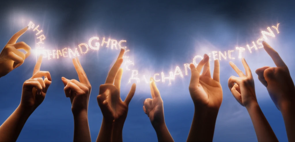 Hands gesturing with words being formed by light.