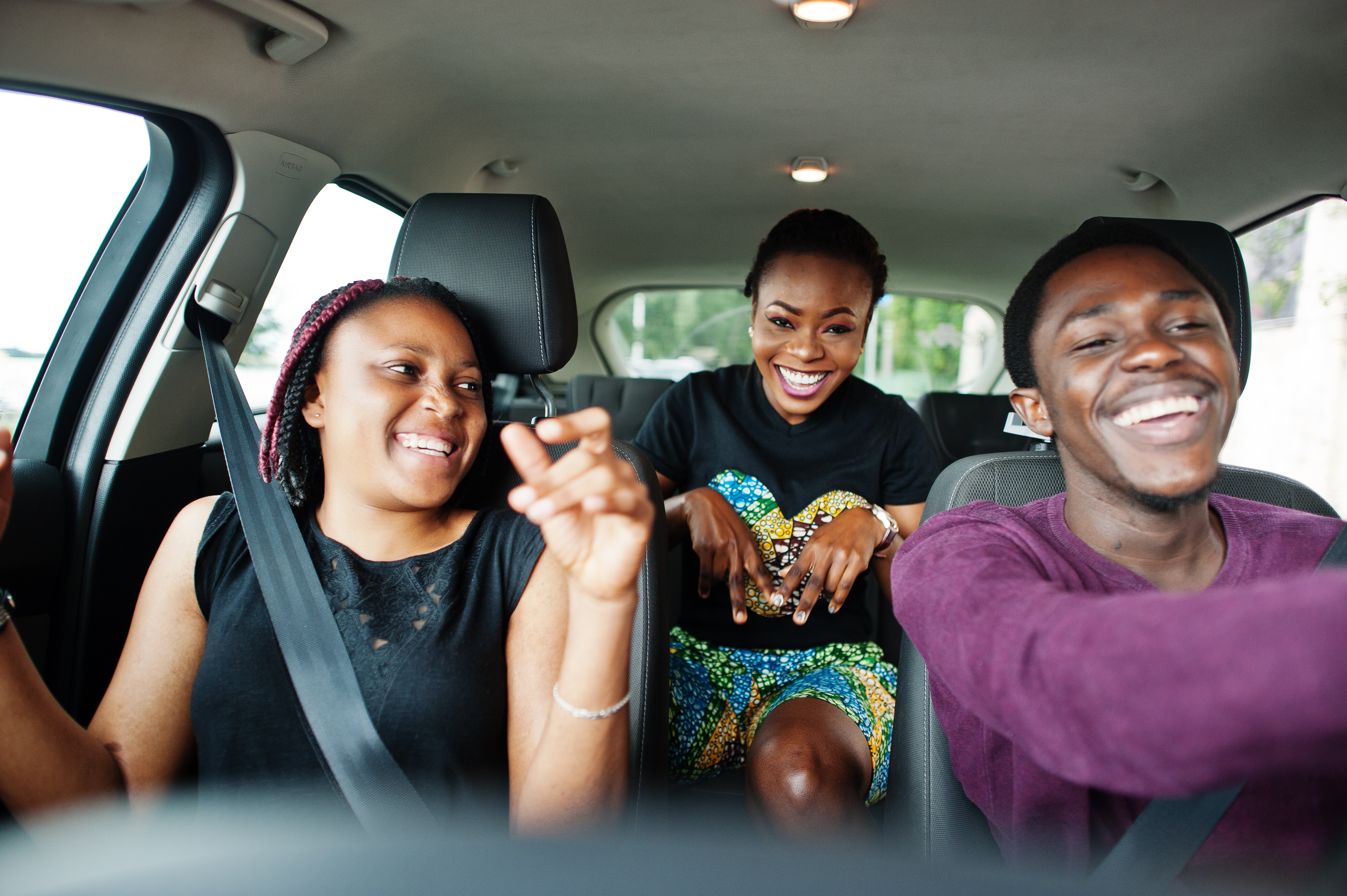 Jeunes amis afro-américains assis dans une voiture, souriants.