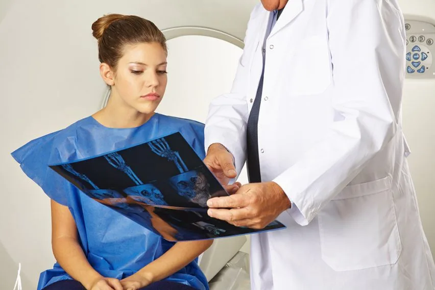 Médico muestra a una trabajadora joven los resultados de unas radiografías durante una evaluación por incapacidad permanente total