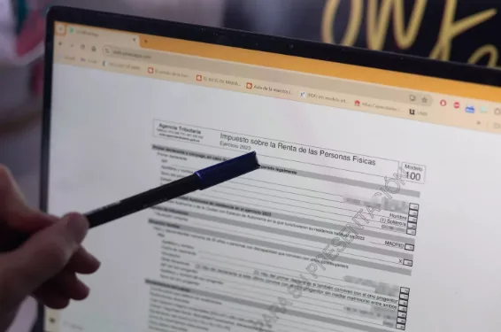 Persona revisando la declaración de la renta en un portátil, rellenando el modelo 100