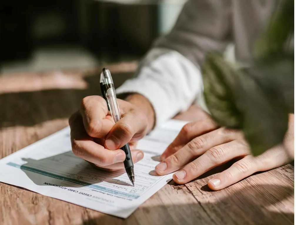 Despido objetivo: mano revisando y firmando documentación para comprobar carta, finiquito y certificado de empresa del SEPE