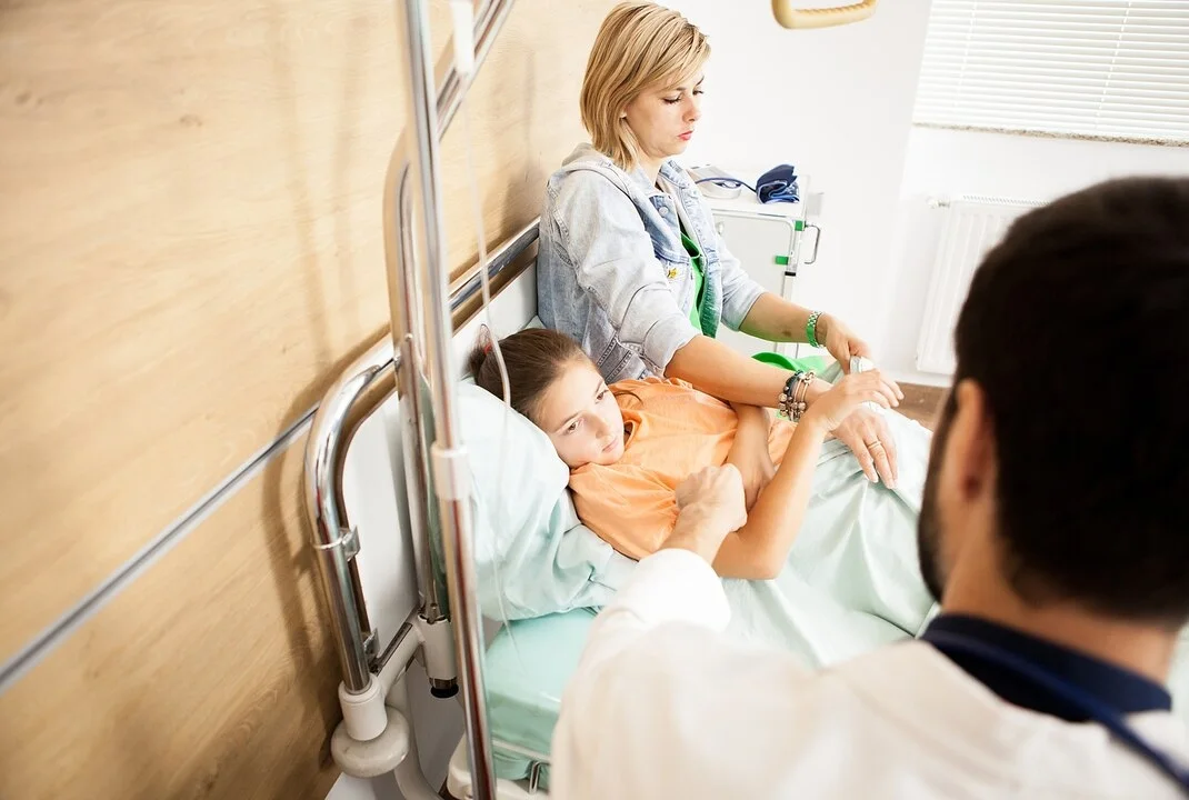 Madre acompañando a su hijo hospitalizado mientras el médico realiza una revisión en la habitación