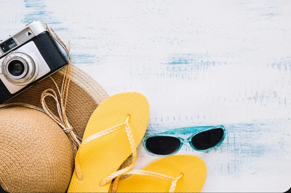 Accesorios de vacaciones de verano y cámara fotográfica clásica sobre superficie de madera con estética playera.