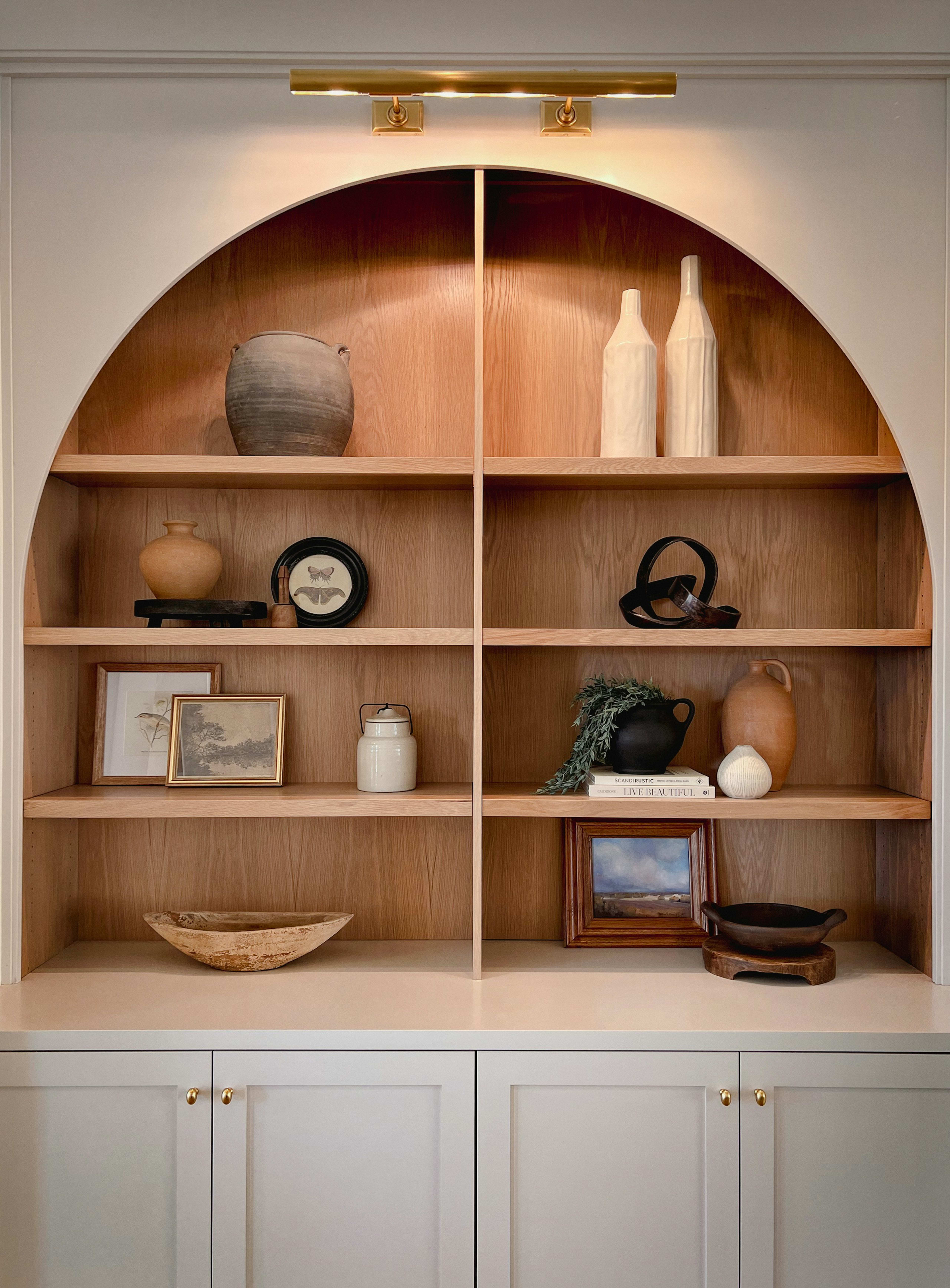 An arched oak shelf styled with ceramics and frames