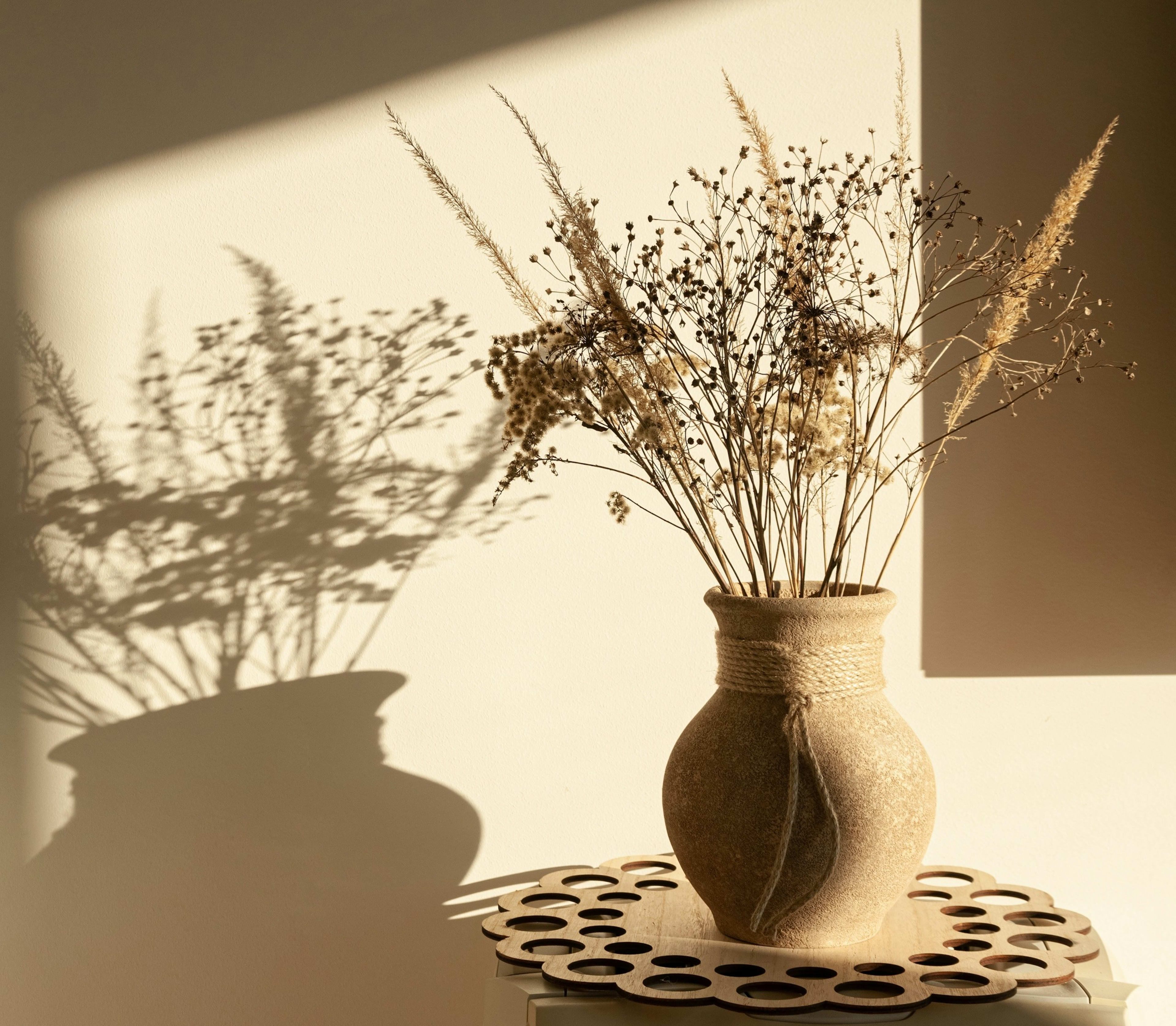 Dried flowers in a textured vase casting shadows