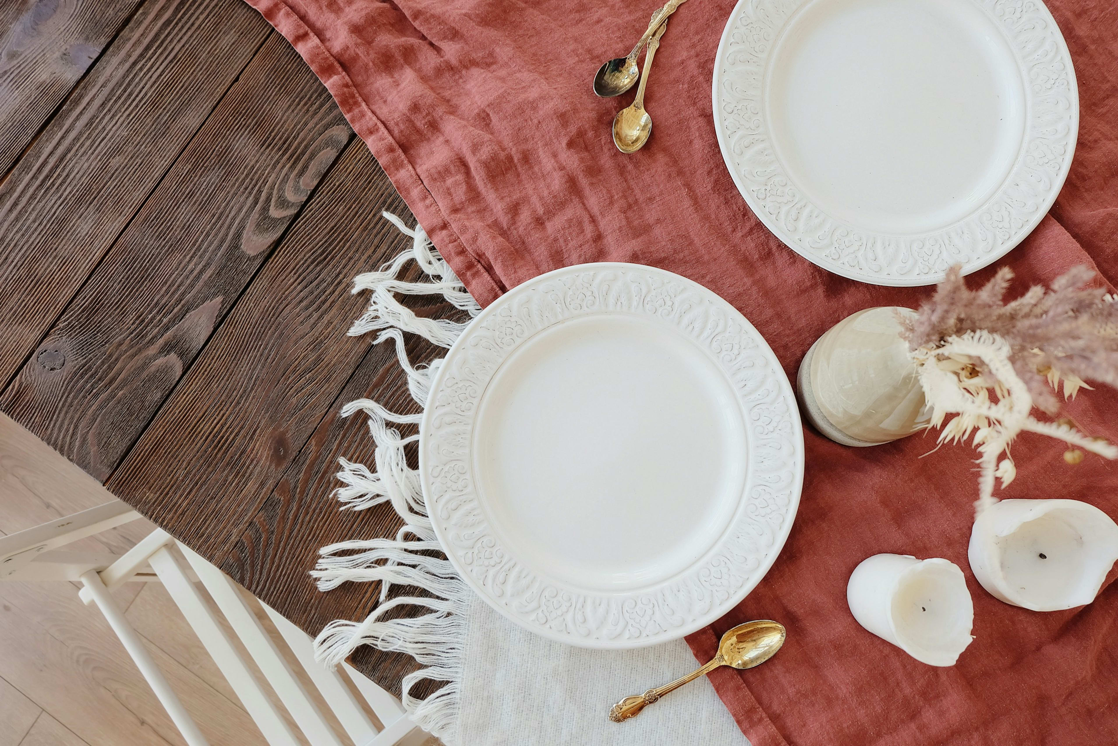 A table laid with terracotta linen and white plates