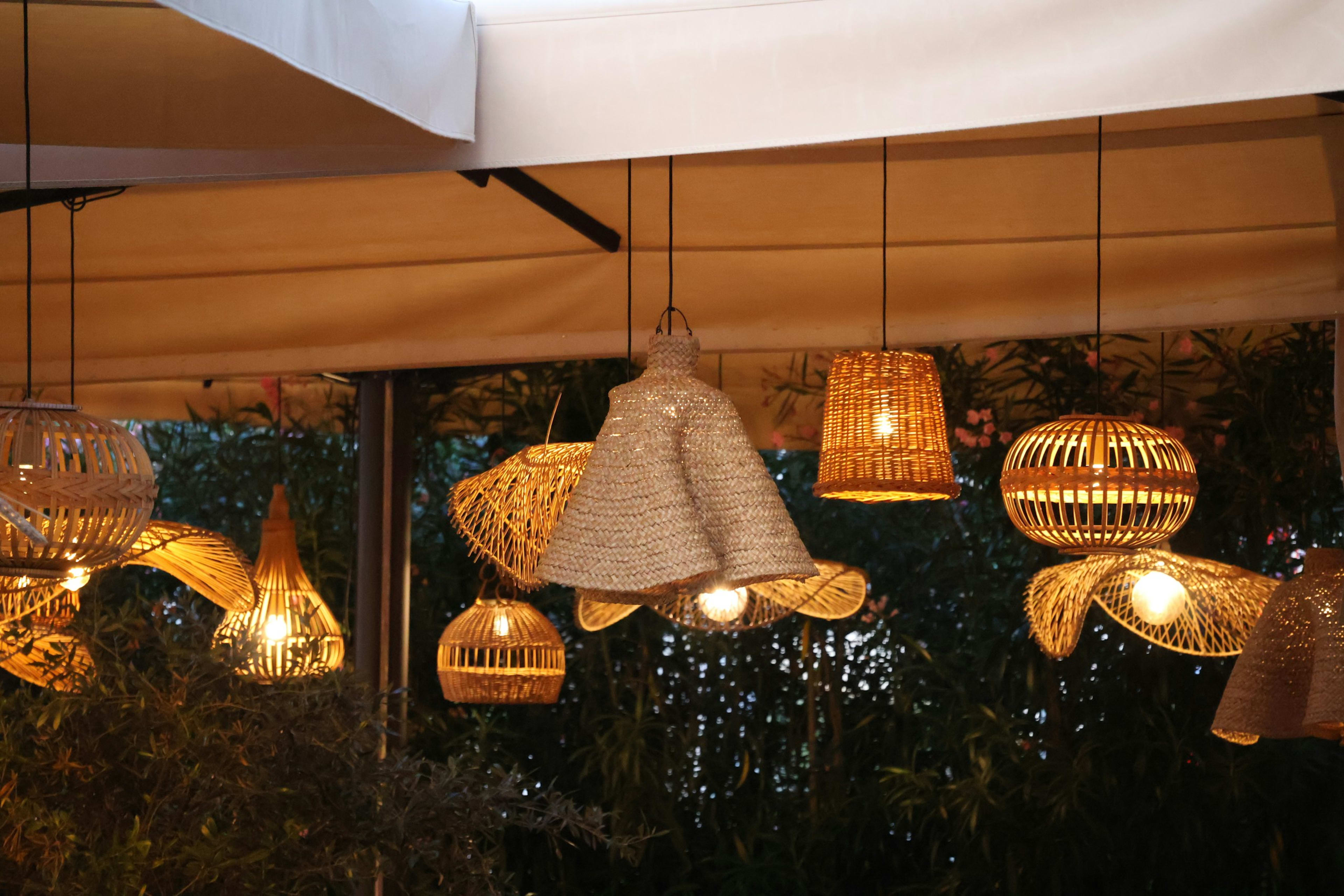 Woven rattan pendant lights glowing at dusk