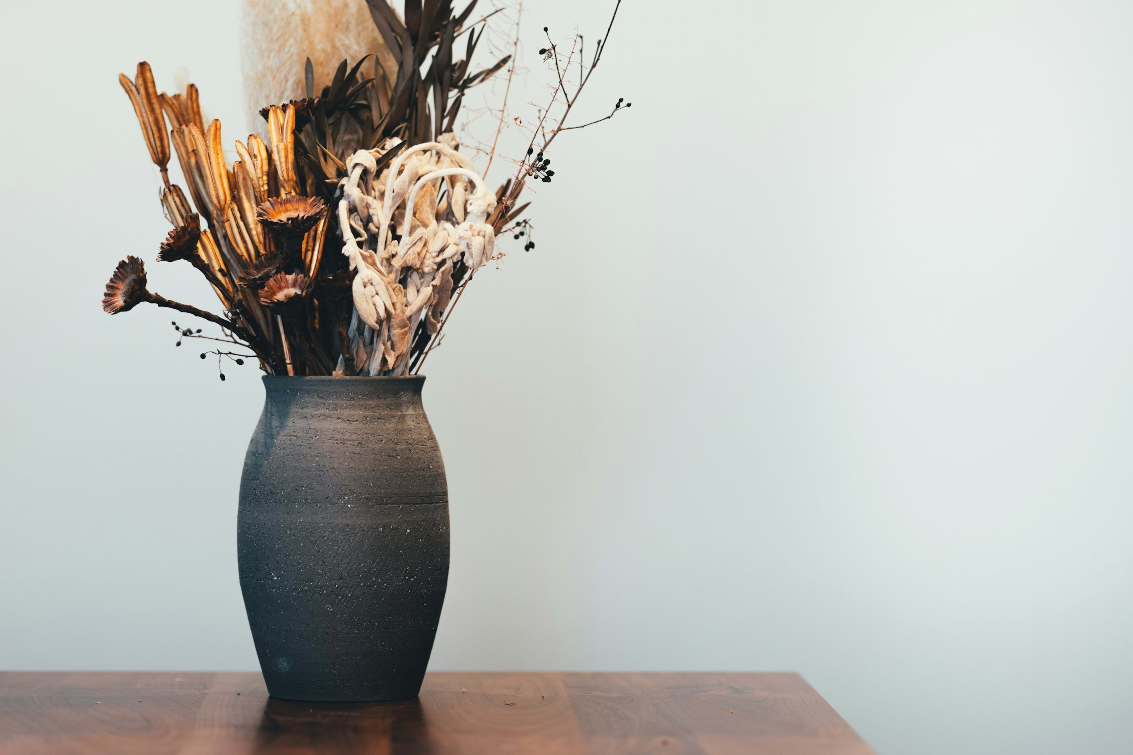 Dried flowers in a dark ceramic vase