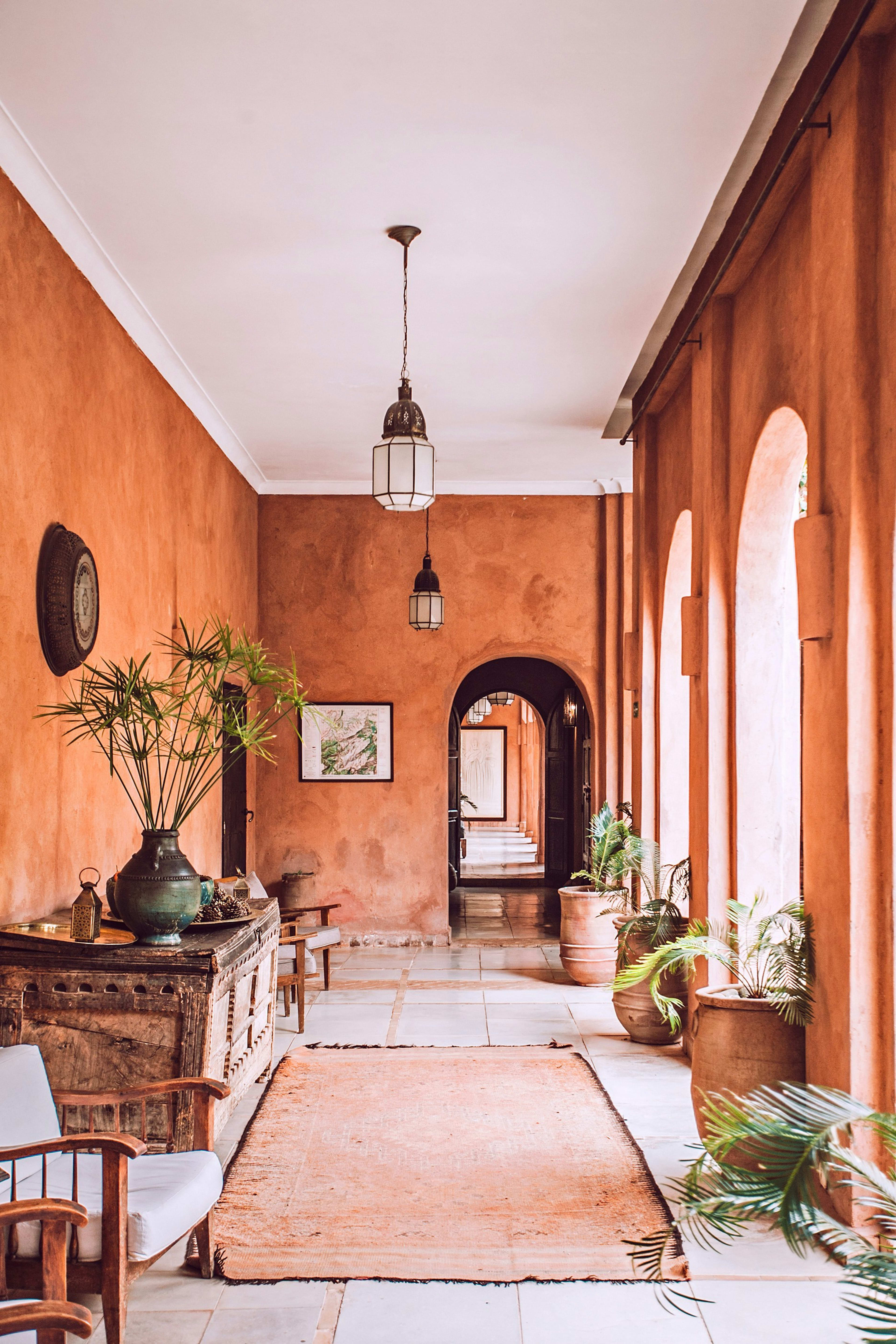 A sunlit terracotta hallway with arches and plants