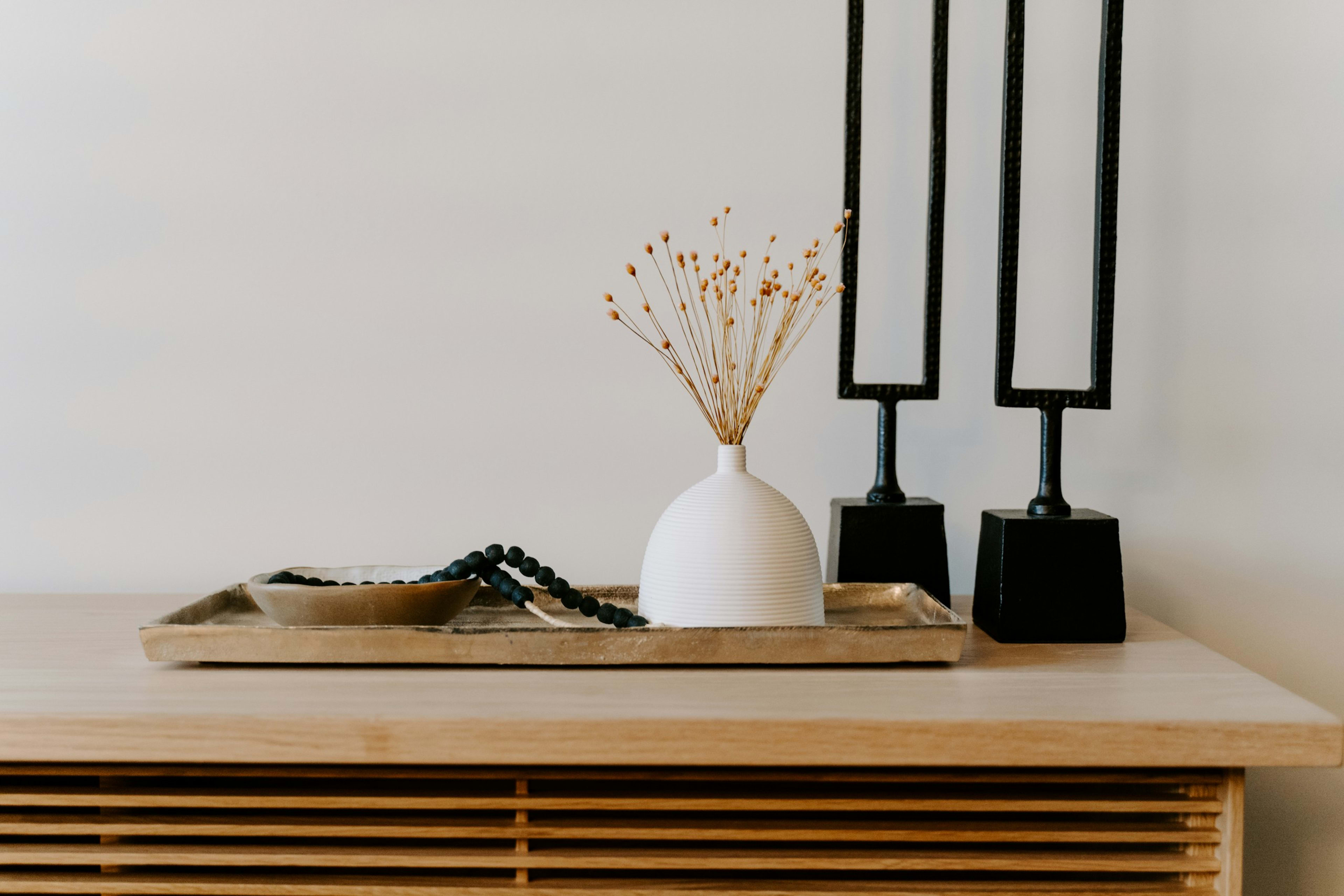 A console styled with a white vase and black candlesticks