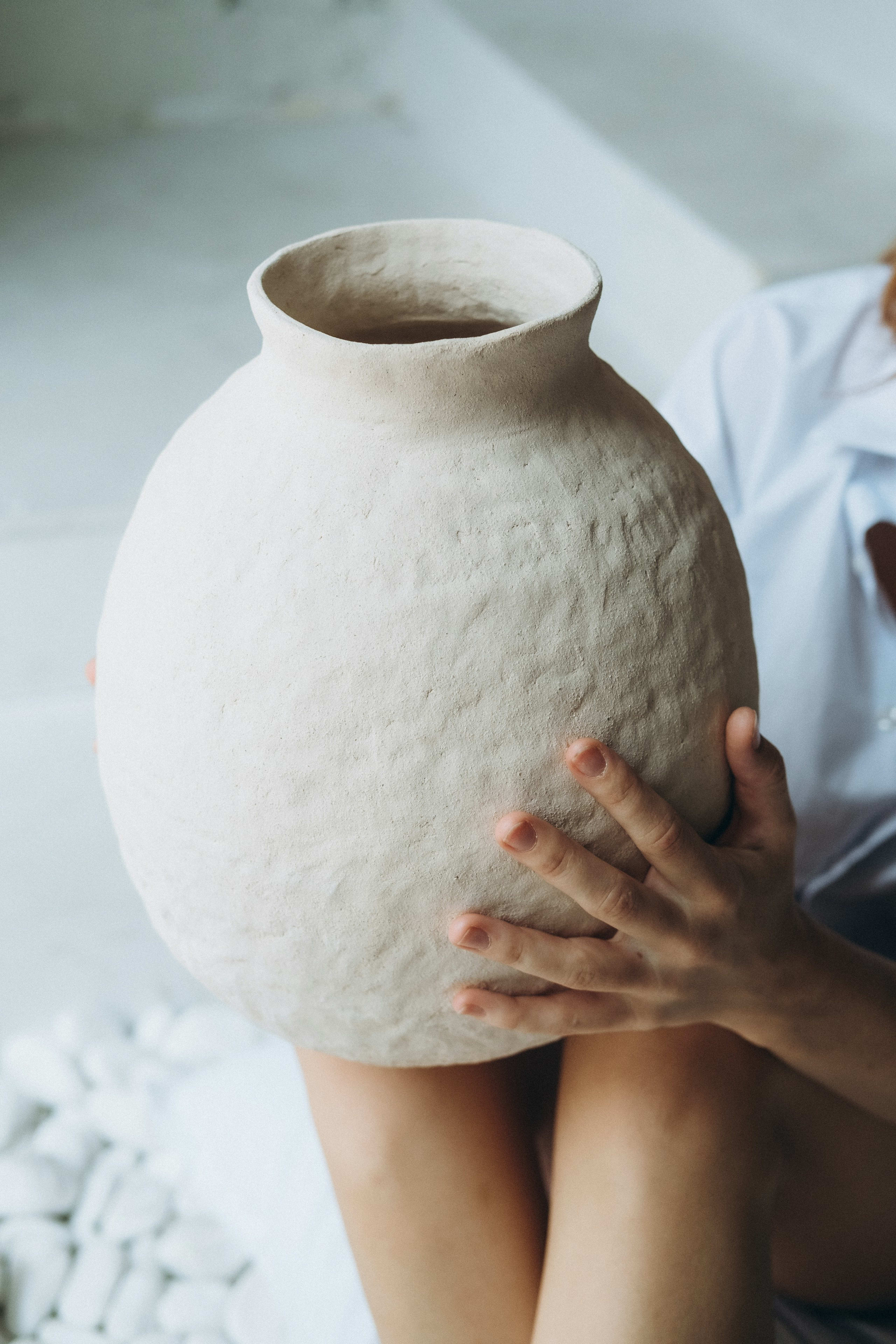 Hands holding a textured ceramic vase