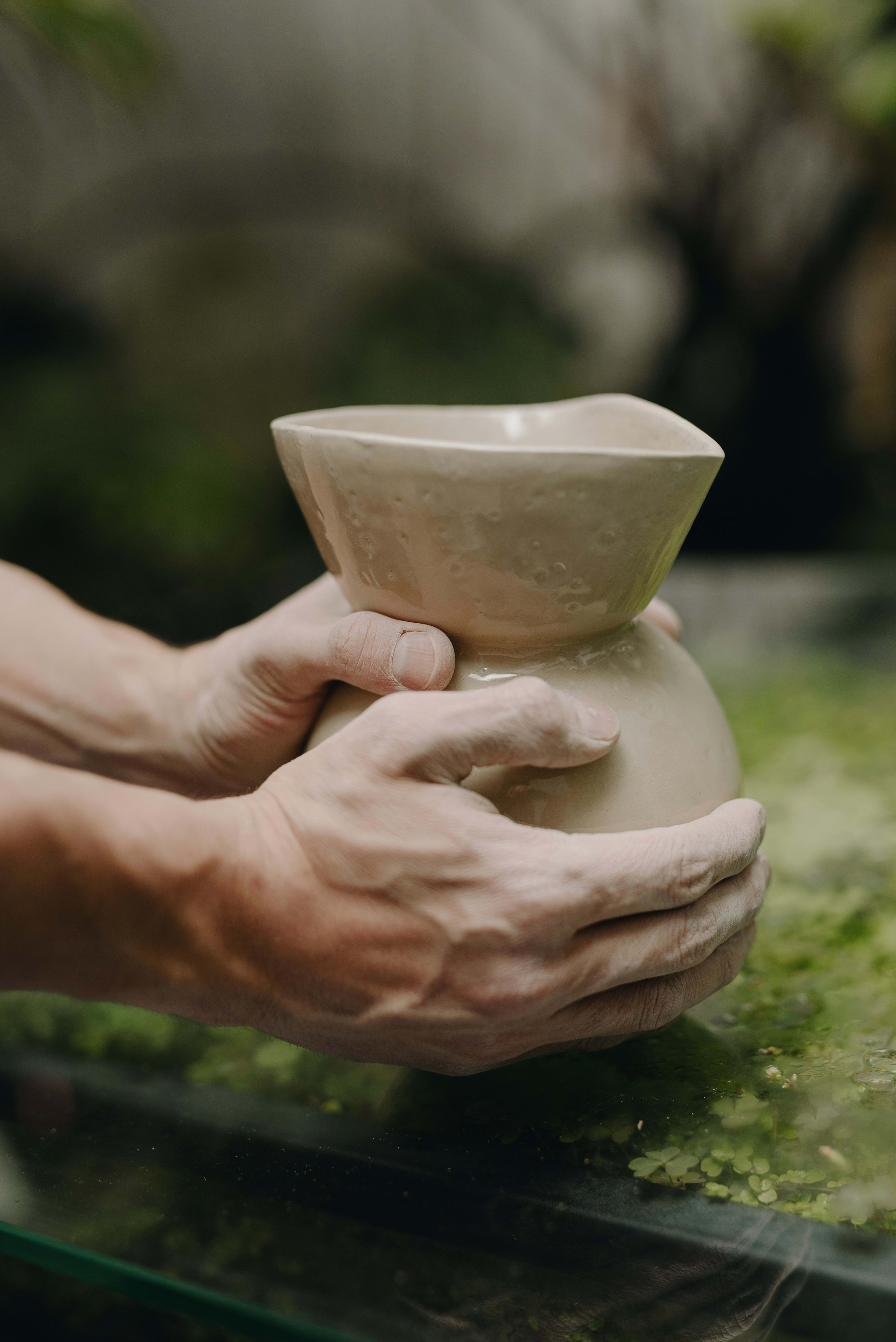 A maker shaping a clay bowl by hand