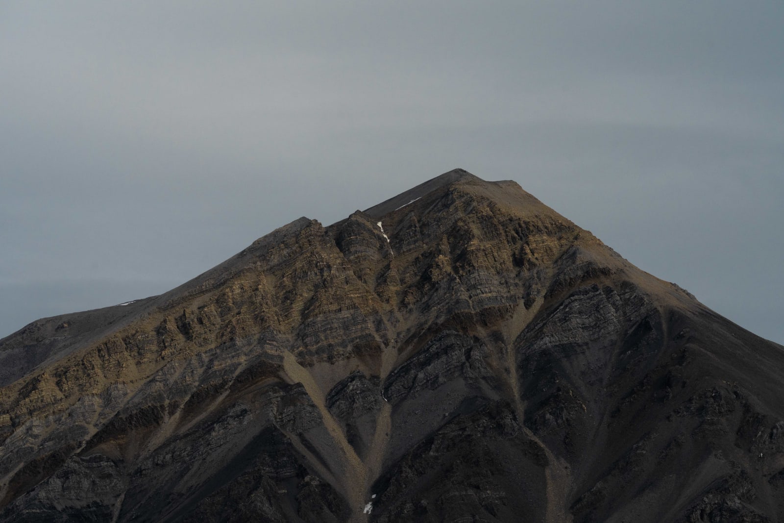 Brown triangular mountain with diagonal lines running through it.