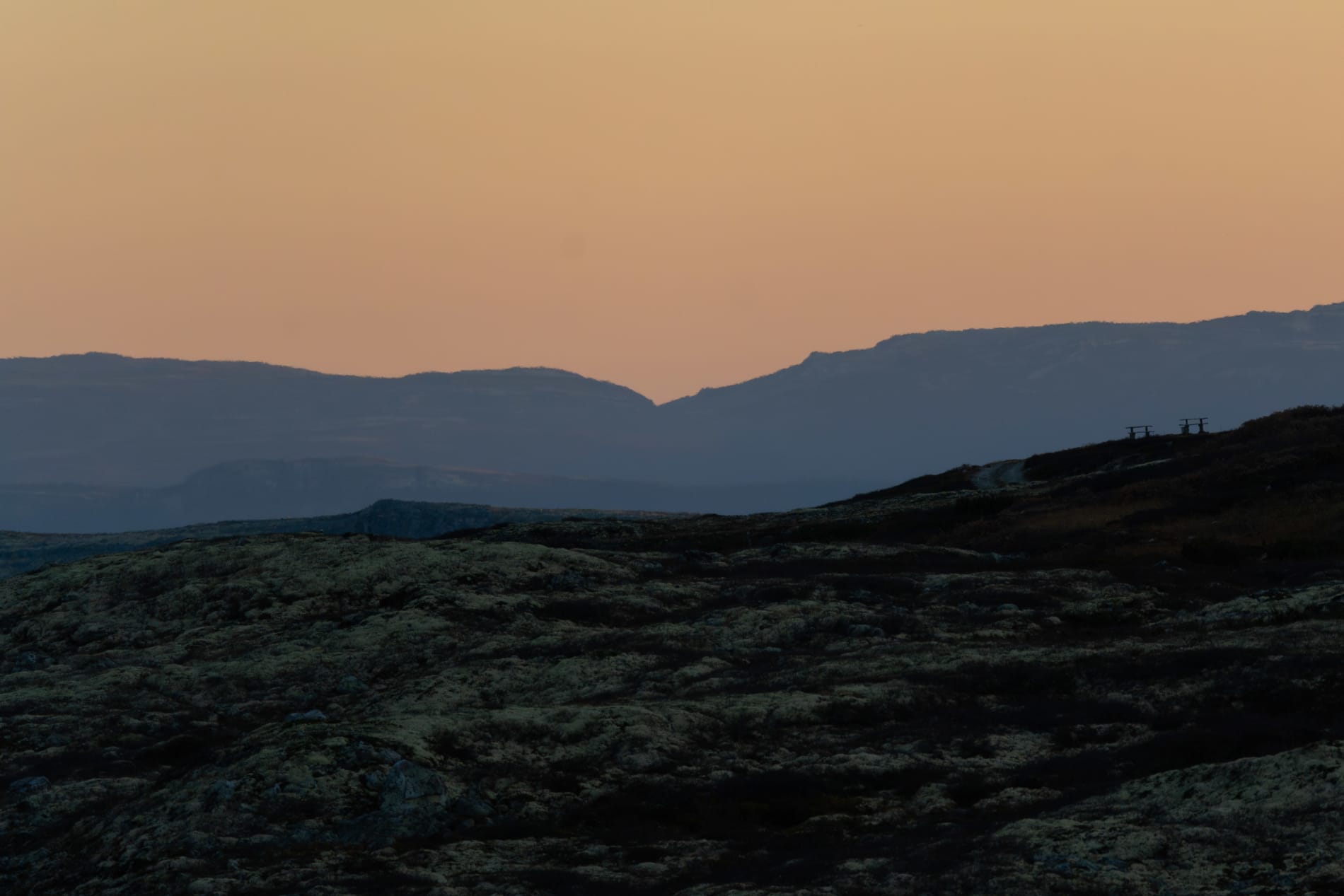 Dark blue layers of mountains (silhouettes in different brightnesses), against an orange sky