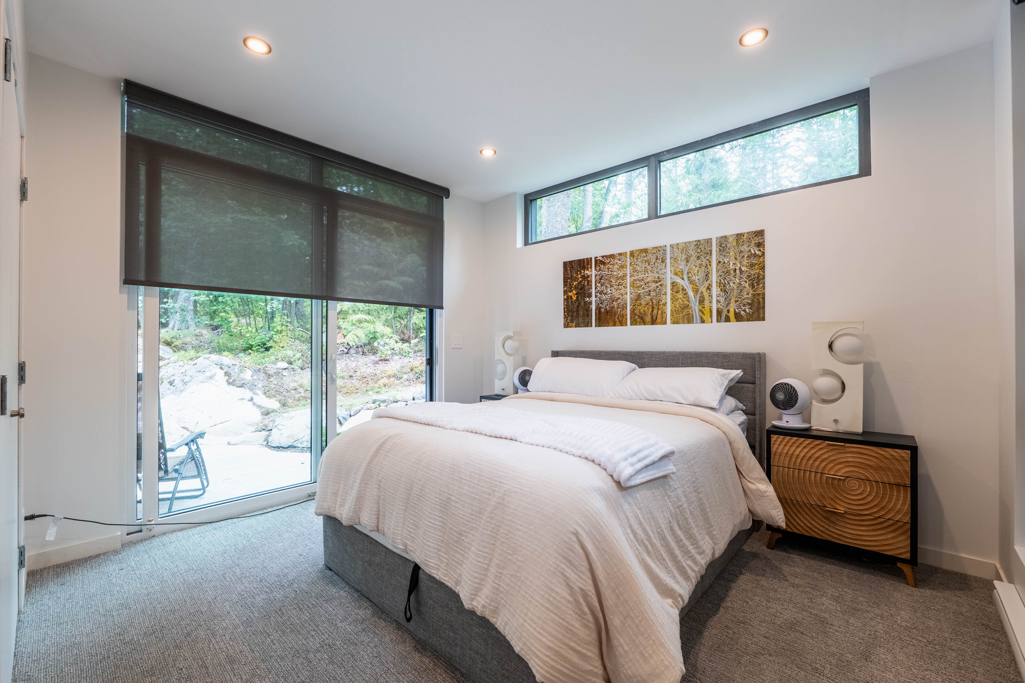 Peaceful bedroom with windows looking into the forest