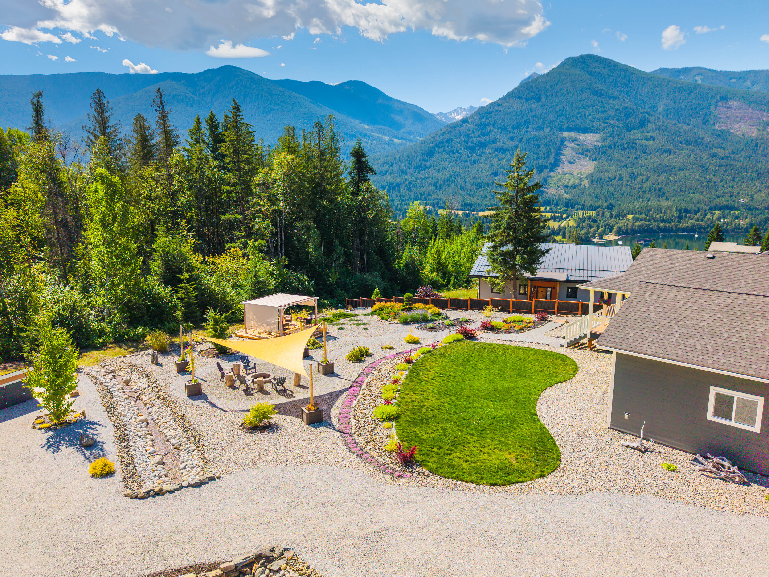 Aerial view of the landscaped outdoor living spaces at 430 Buriview Drive with Kootenay Lake and mountain scenery beyond