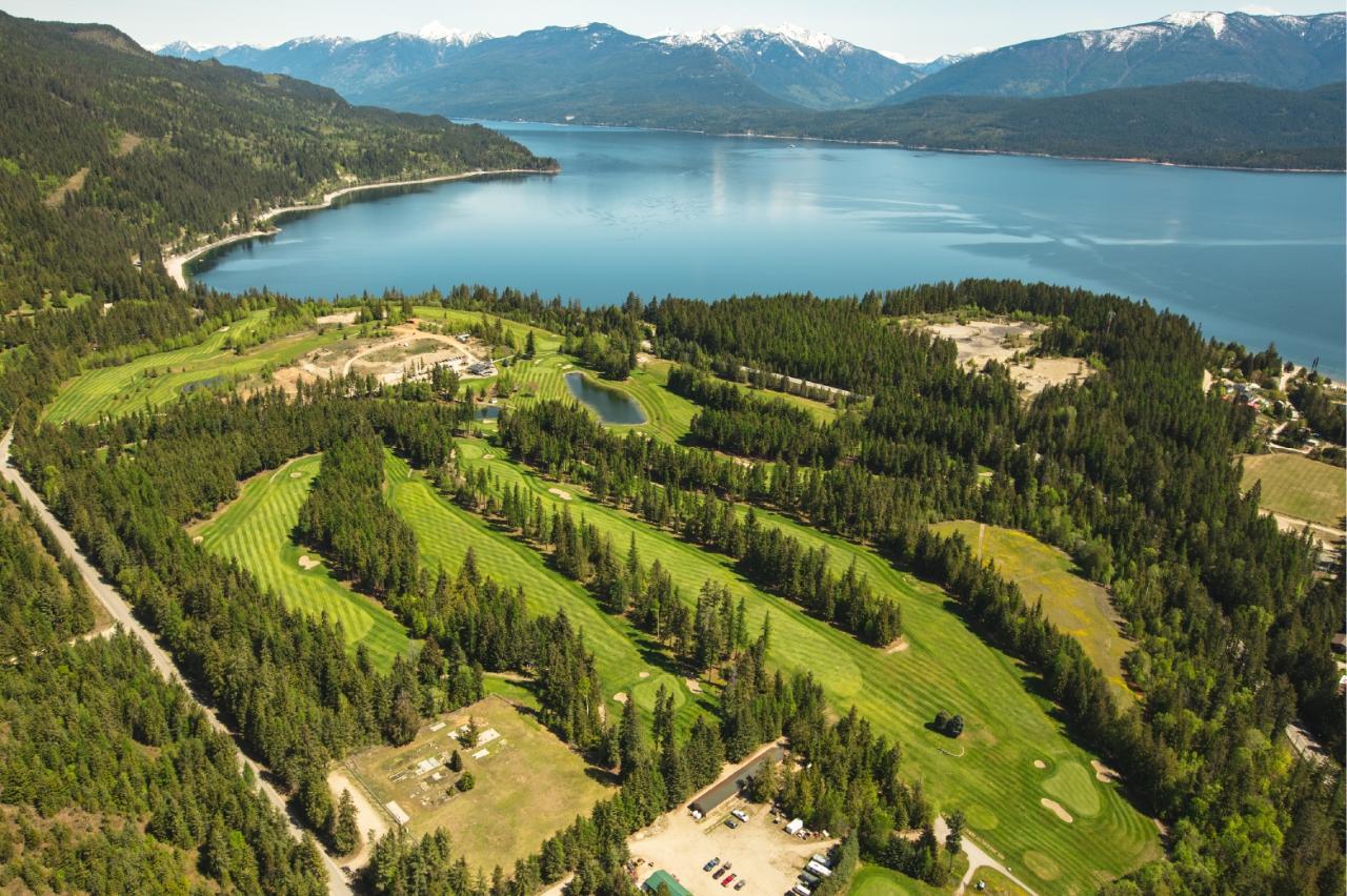 Aerial view of Balfour Golf Course and Kootenay Lake surrounded by mountains