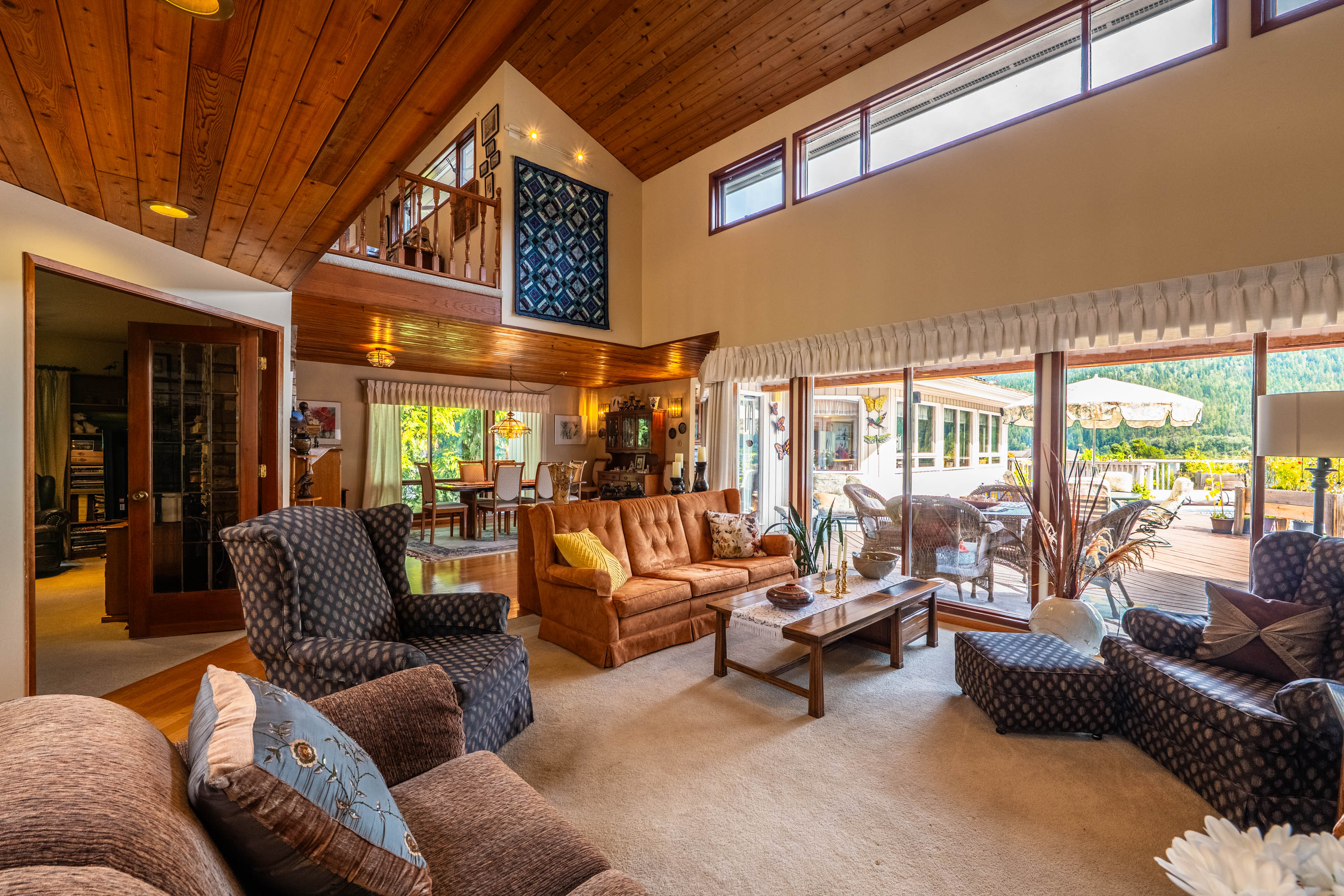 Main living area with vaulted wood ceiling and expansive windows