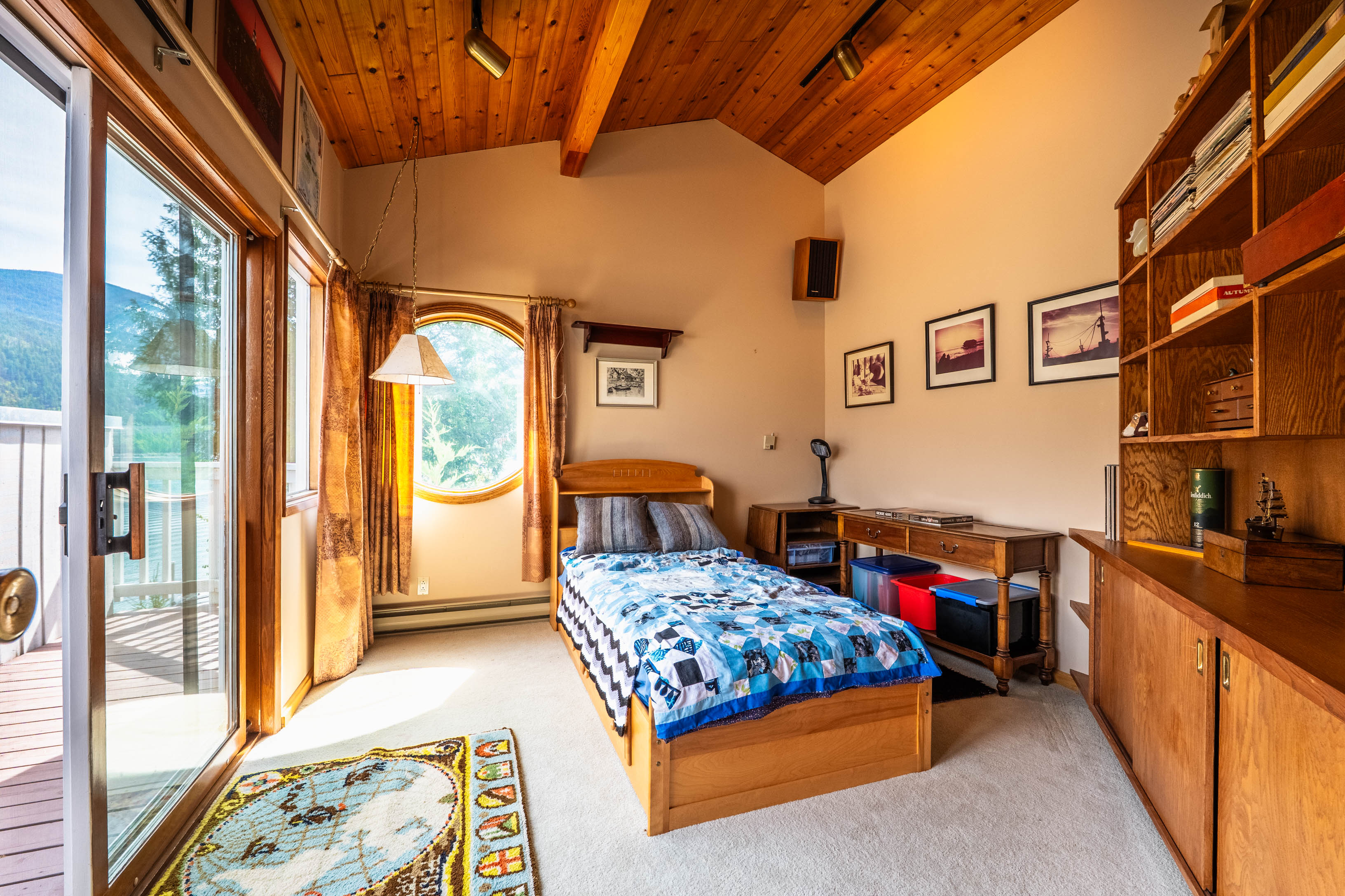 Guest bedroom with vaulted wood ceiling and deck access
