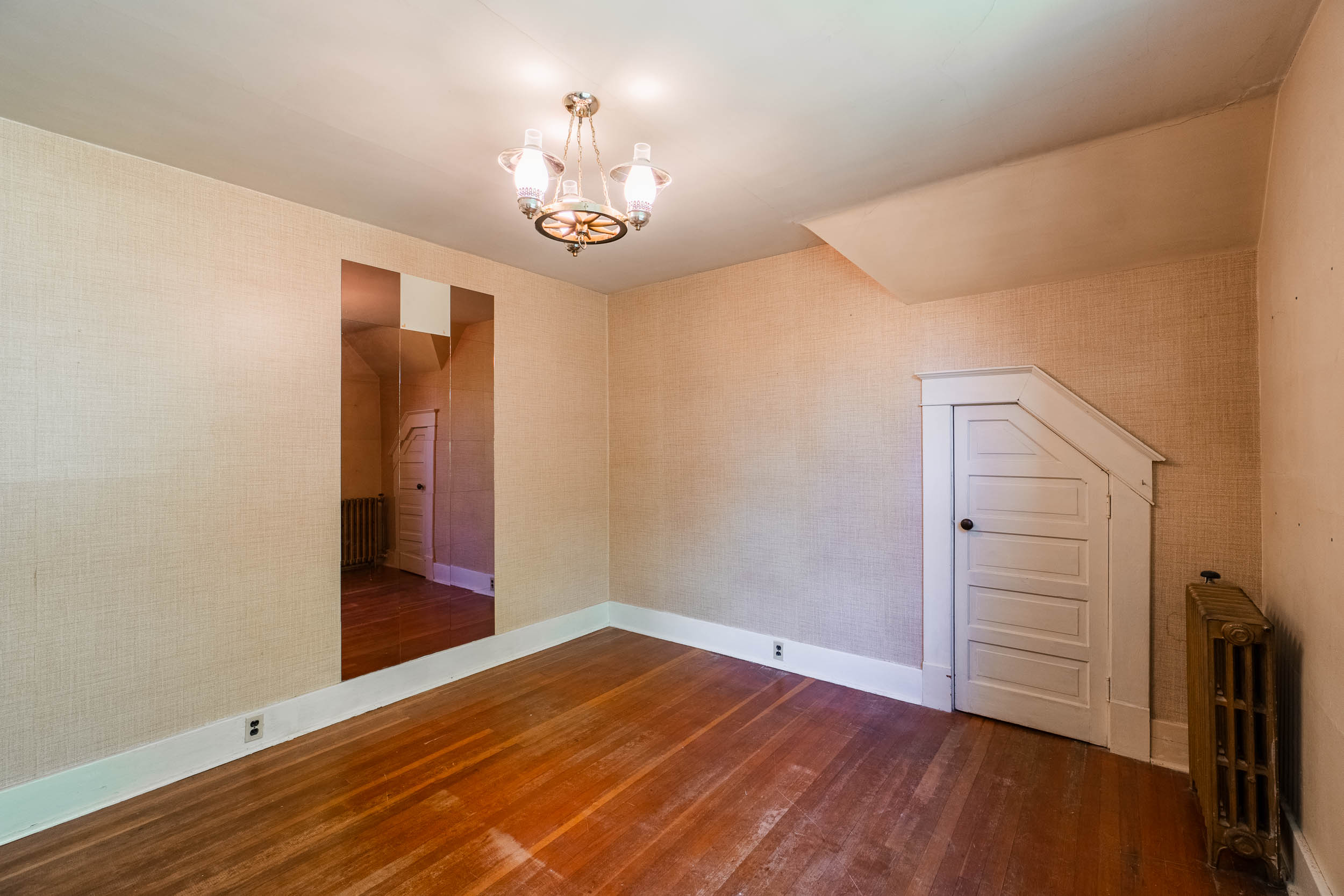 Bedroom with hardwood flooring, original radiator and built-in under-eave storage