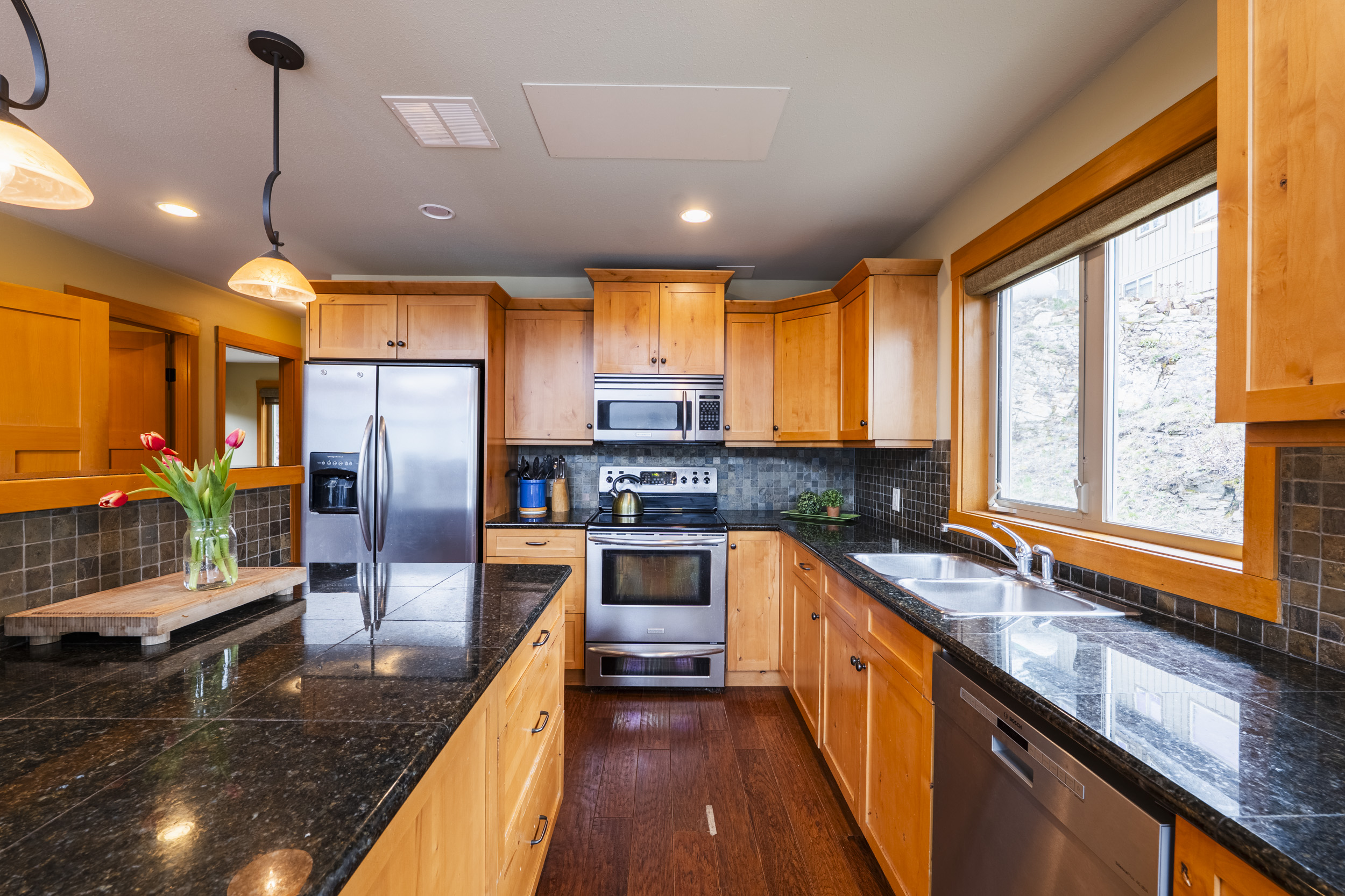 Kitchen with wood cabinetry and dark stone counters