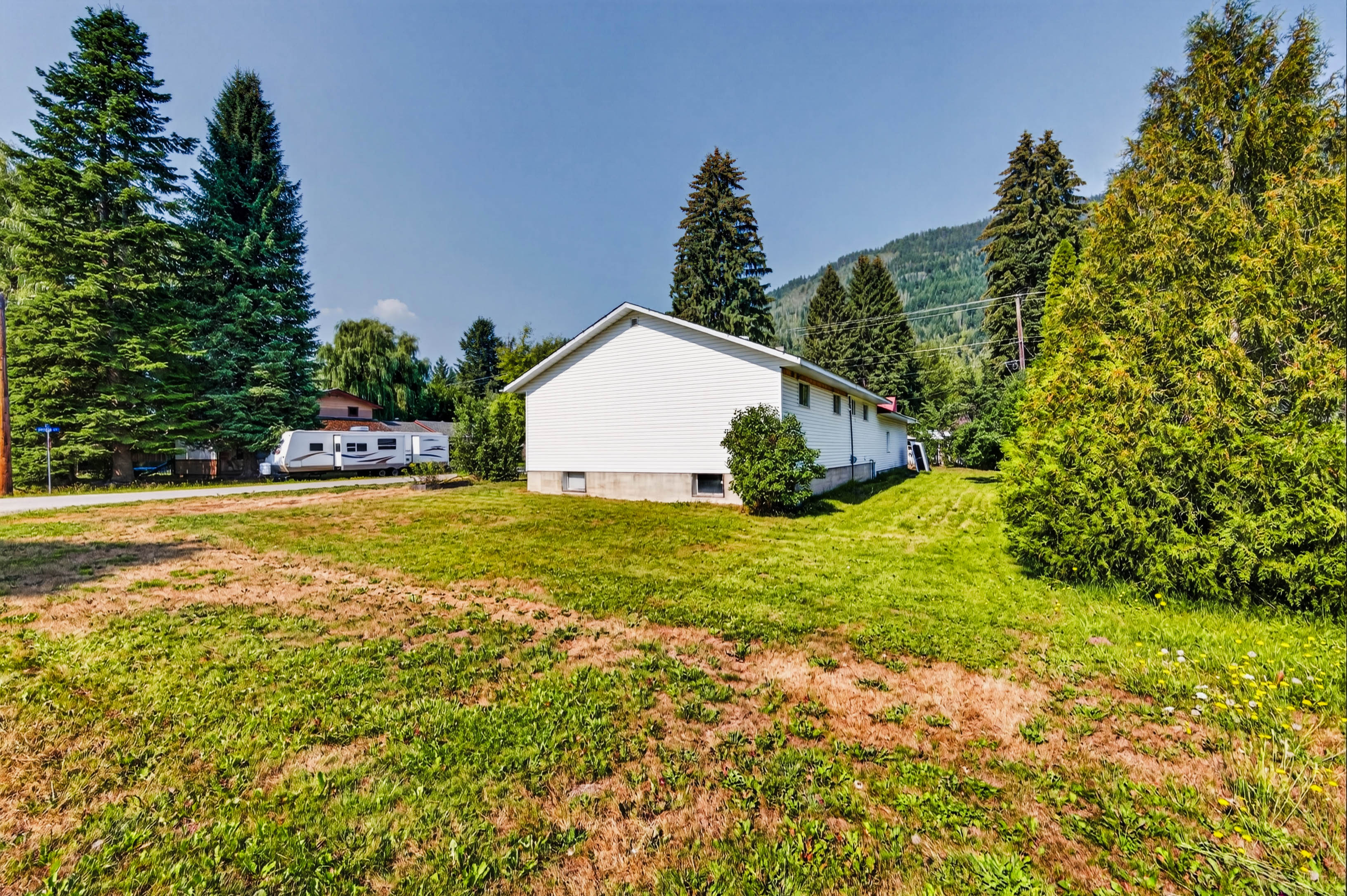 Side exterior of the home with open yard and mountain backdrop