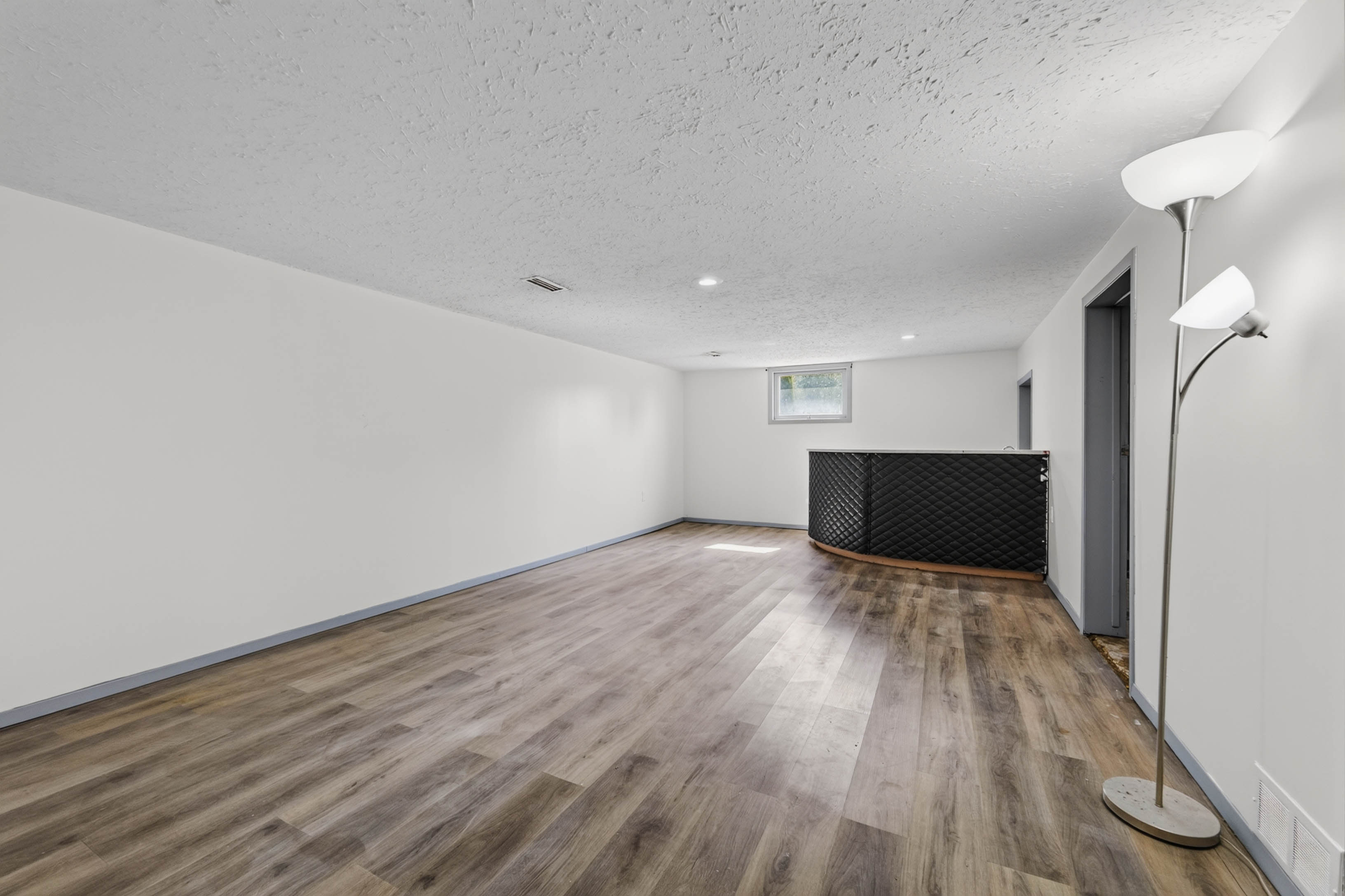 Open lower-level recreation room with wood-look flooring