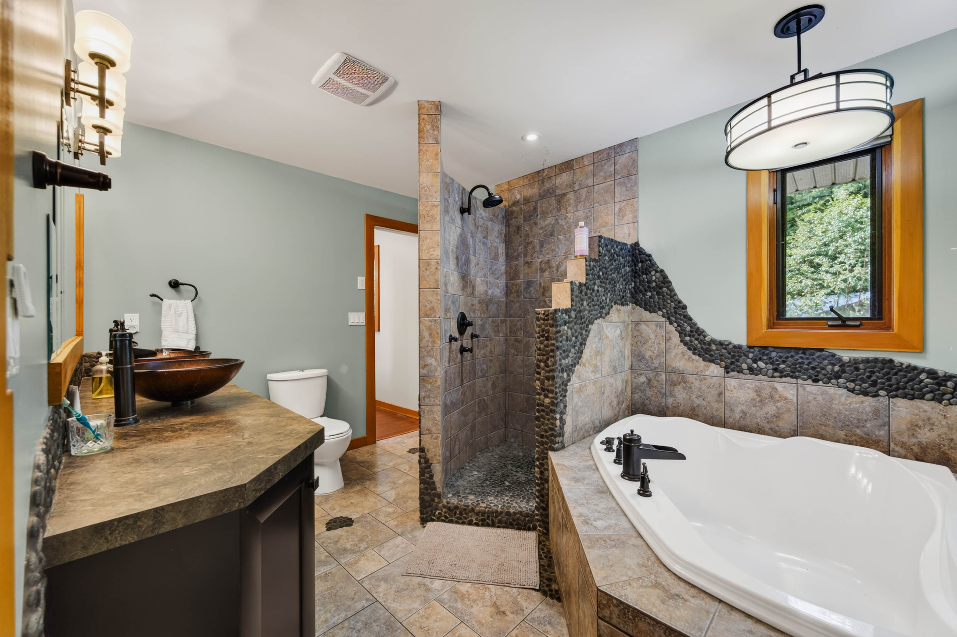Bathroom at 3360 Little Slocan South Road featuring a large soaker tub, separate tiled shower, vessel sink and detailed stone and tile finishes.