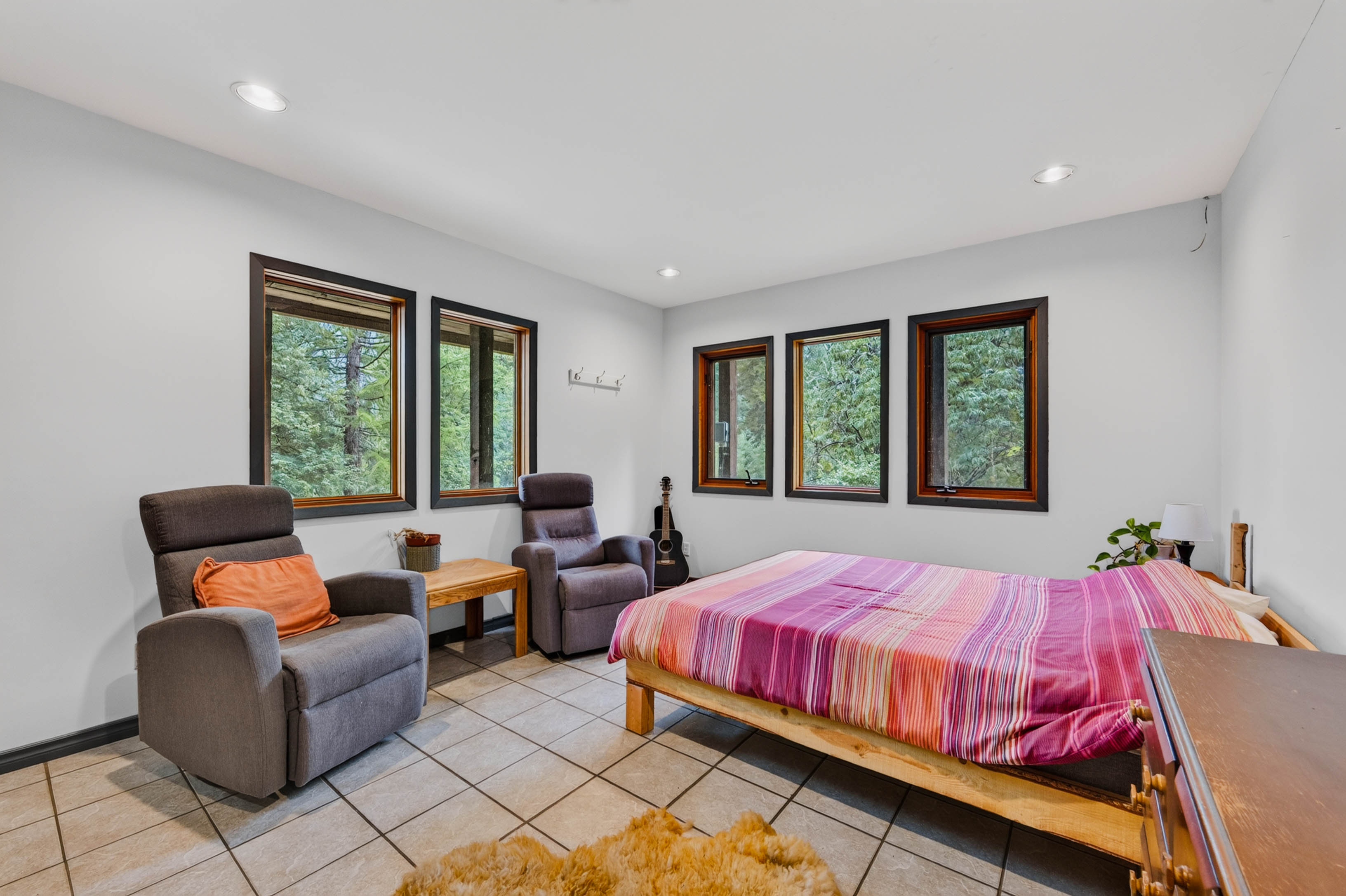 Bedroom at 3360 Little Slocan South Road with multiple windows overlooking the surrounding forest.