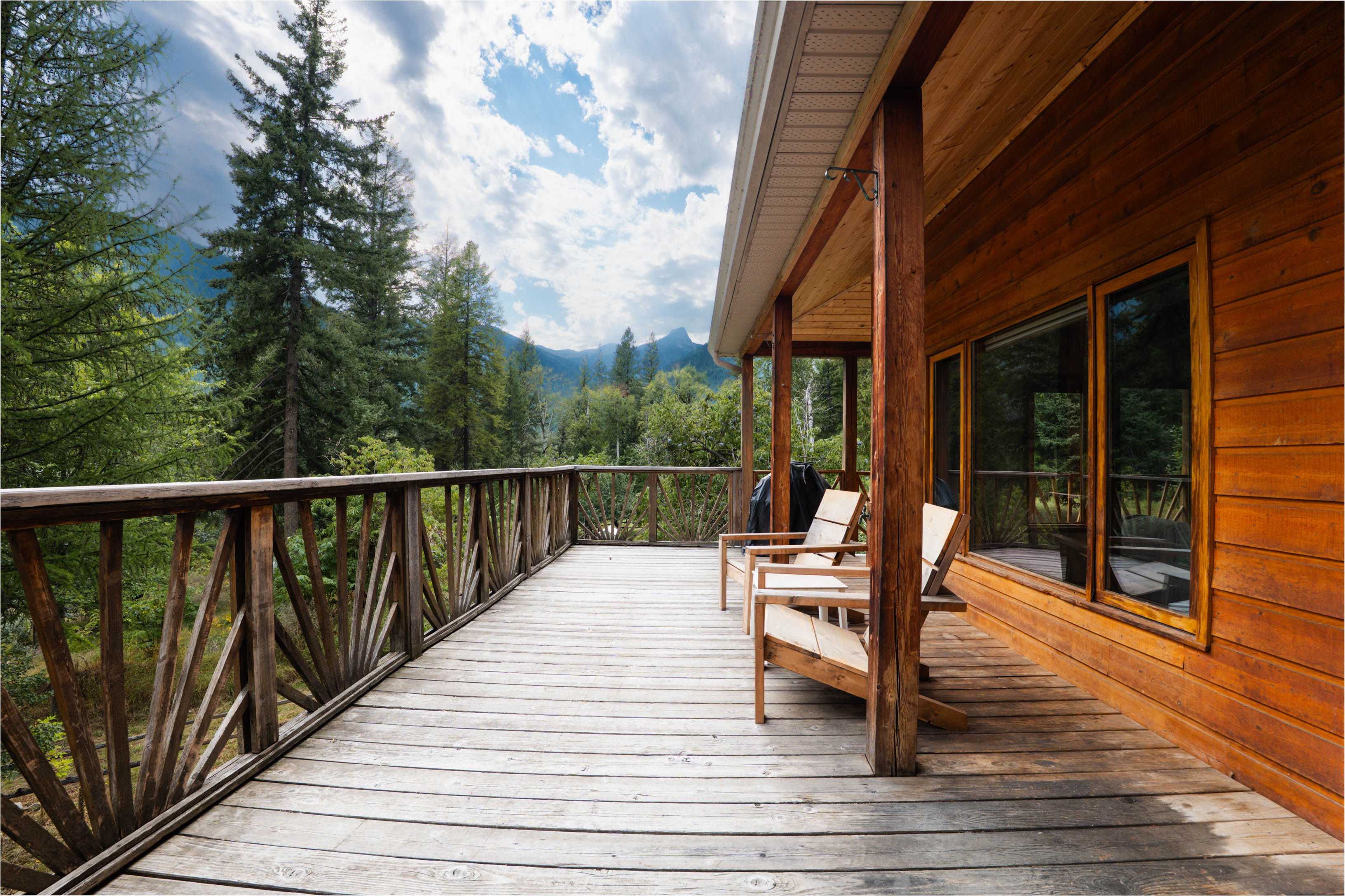 Wood deck at 3360 Little Slocan South Road with seating and views toward the surrounding forested mountains.
