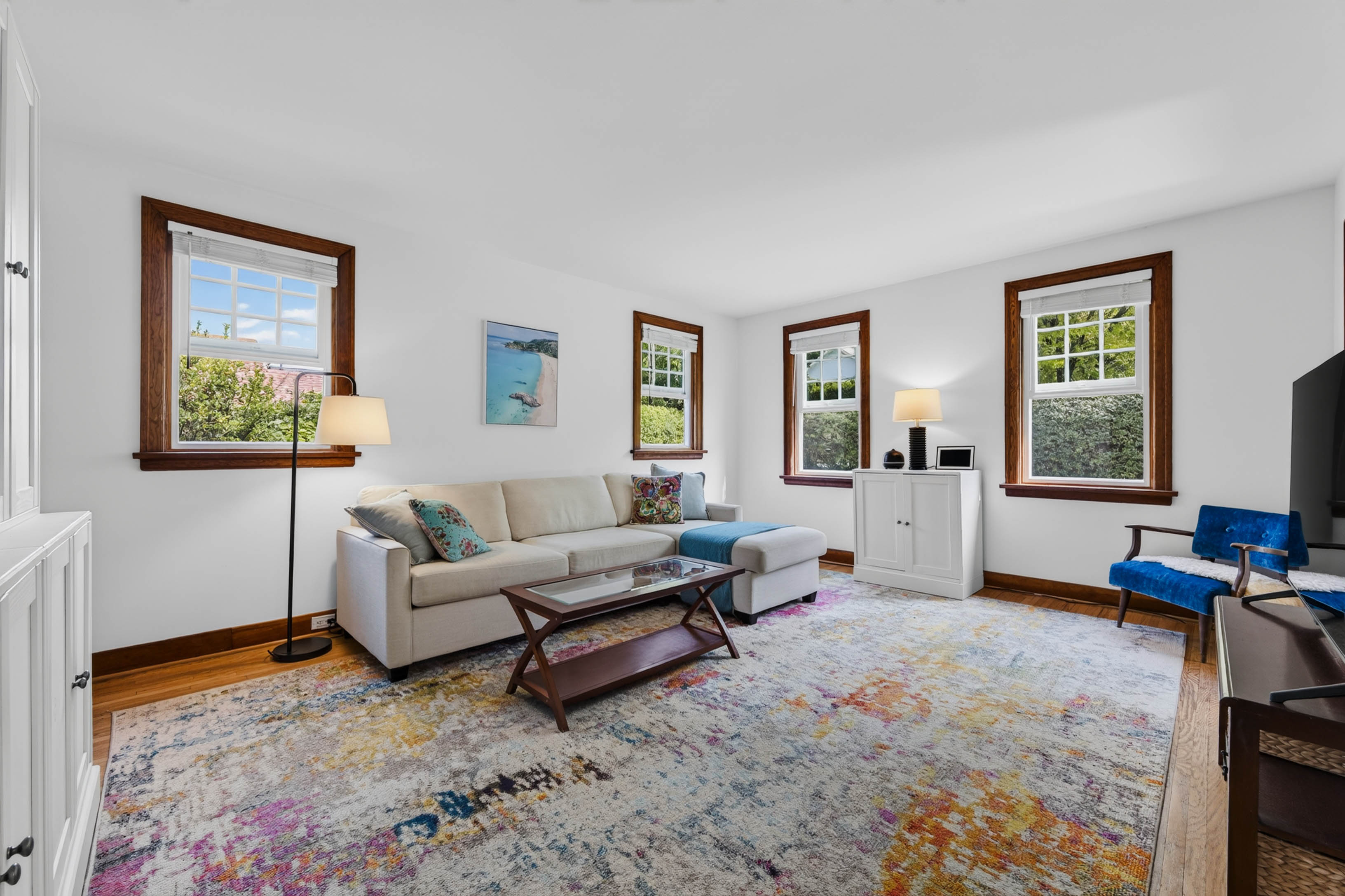 Main living room with wood-trimmed windows, white walls and original wood flooring