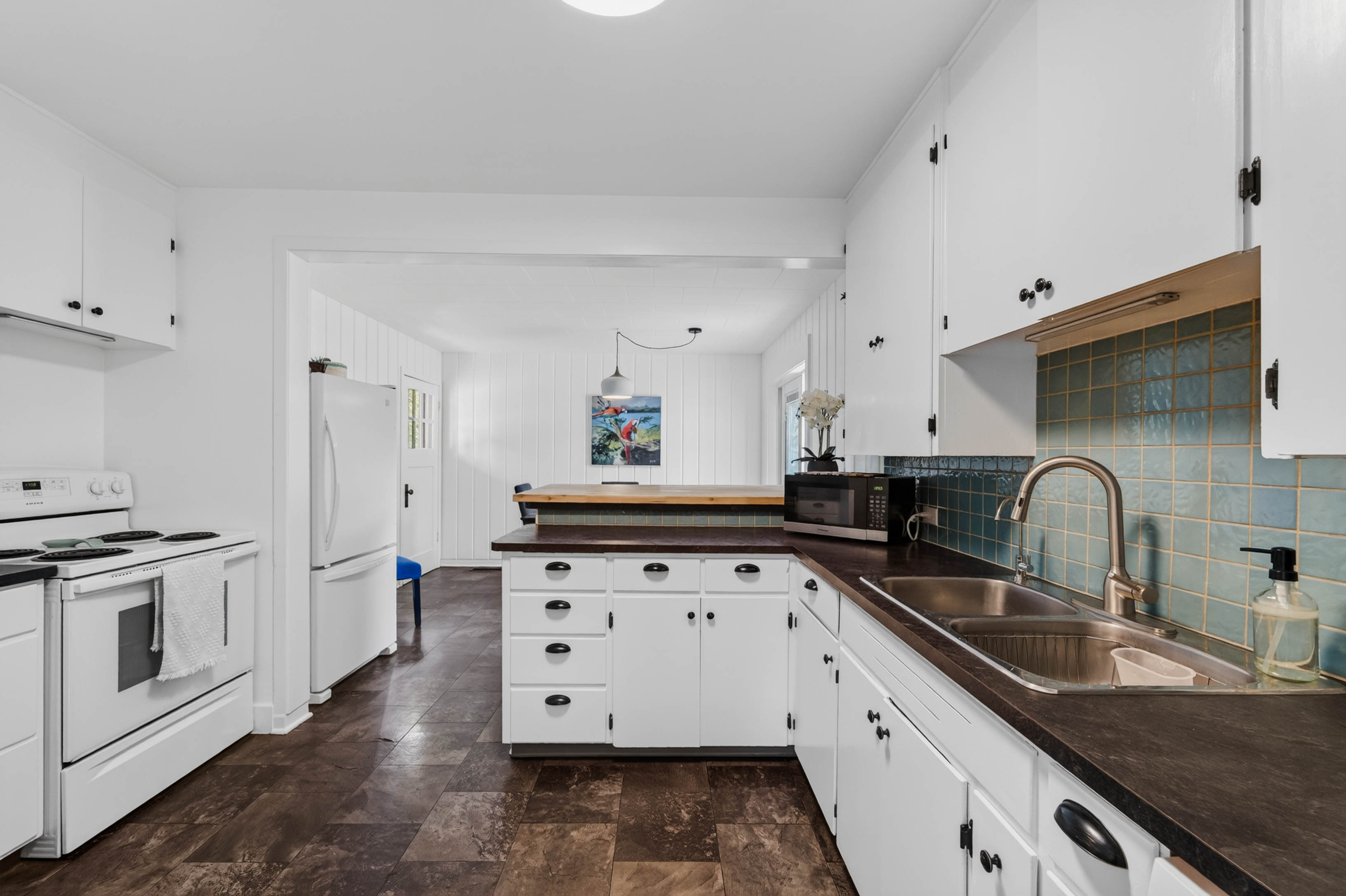 Main kitchen with white cabinetry and teal tile backsplash