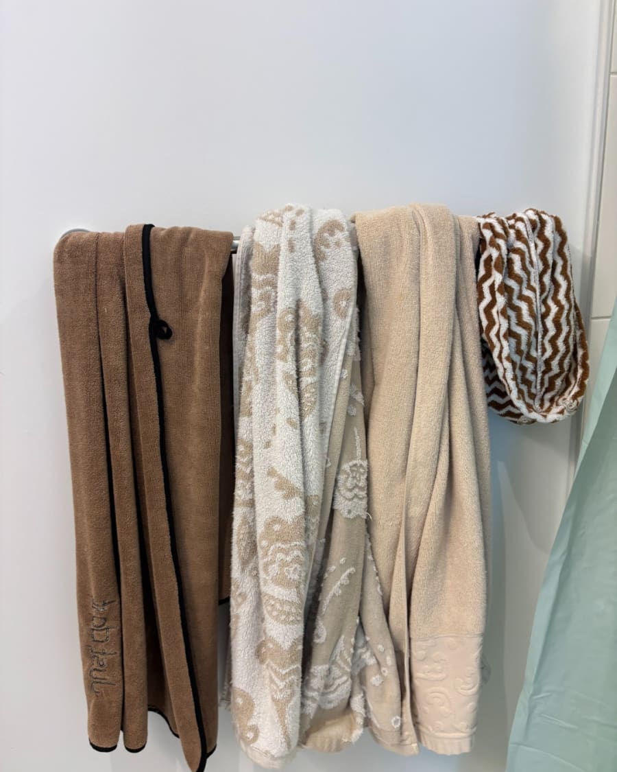 A bathroom with used towels and clutter before cleaning