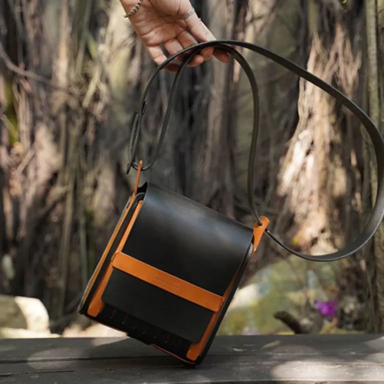 Professional studio photography of a premium leather satchel, focusing on the refined stitching and golden brass hardware.
