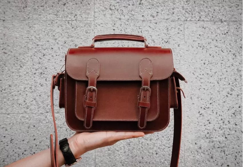 Professional studio photography of a small premium leather crossbody bag, minimalist design, high-quality grain leather.