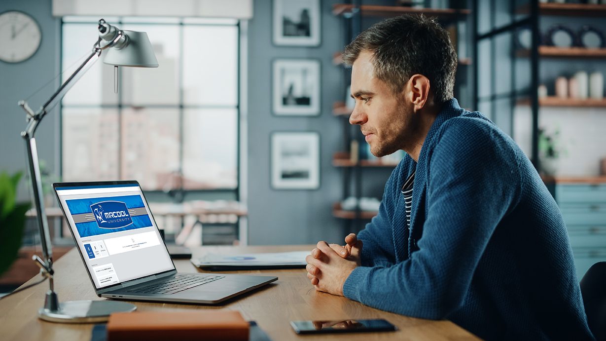 A man on his laptop, looking at the MRCOOL university webpage