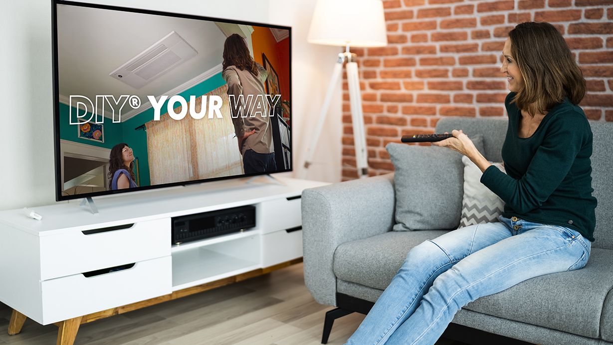A woman sitting on the souch watching a MRCOOL Ad