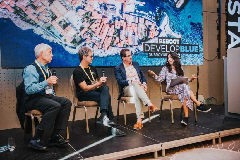 Member of the Kythera AI team participating in a talk on stage at Reboot Develop Blue 2022, against a backdrop of Dubrovnik