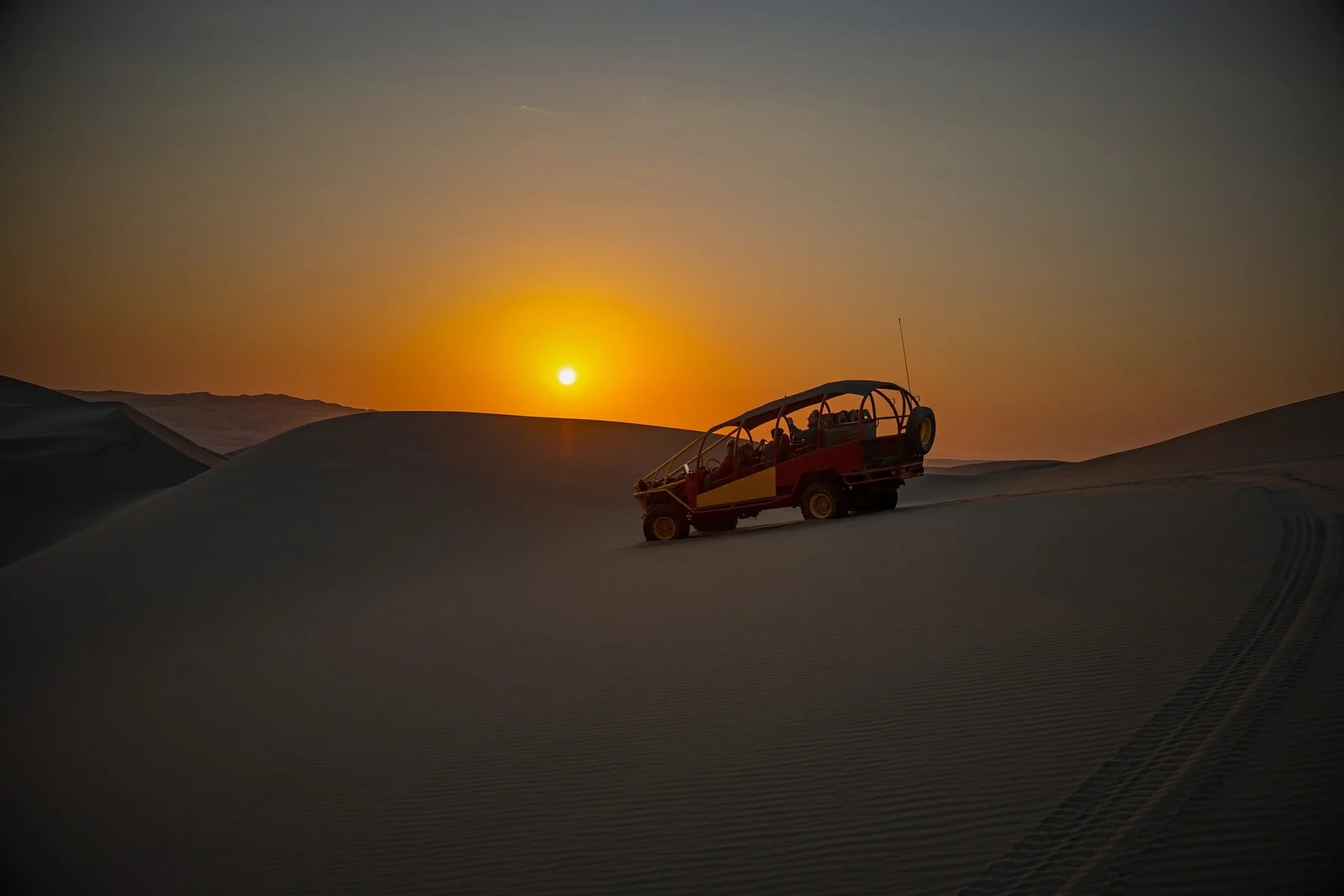Sand dunes of Huacachina glowing orange at golden hour
