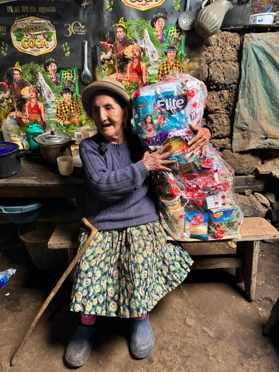 An elder holding a wrapped gift basket of groceries and supplies