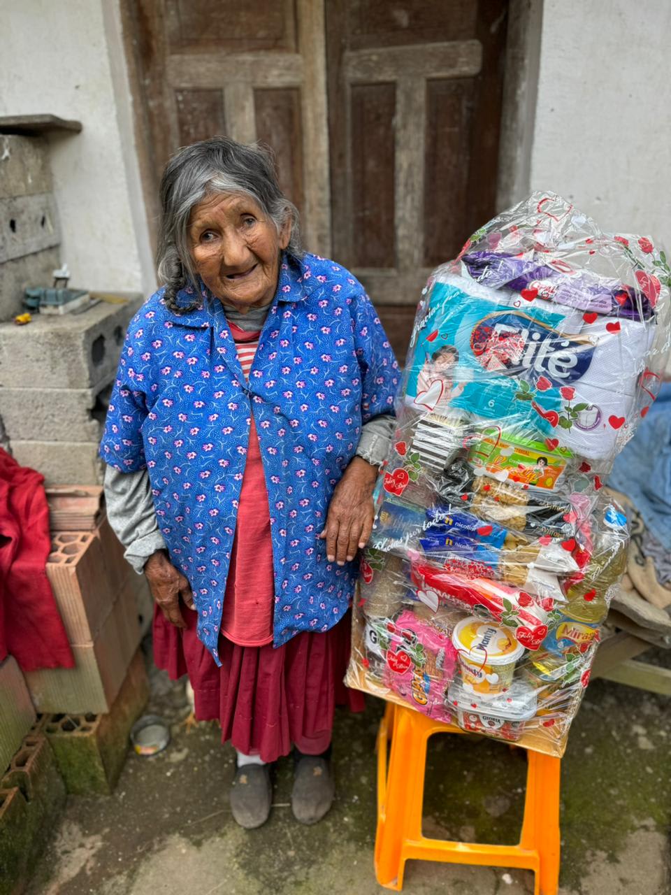 An elder standing beside a wrapped gift basket of donated supplies