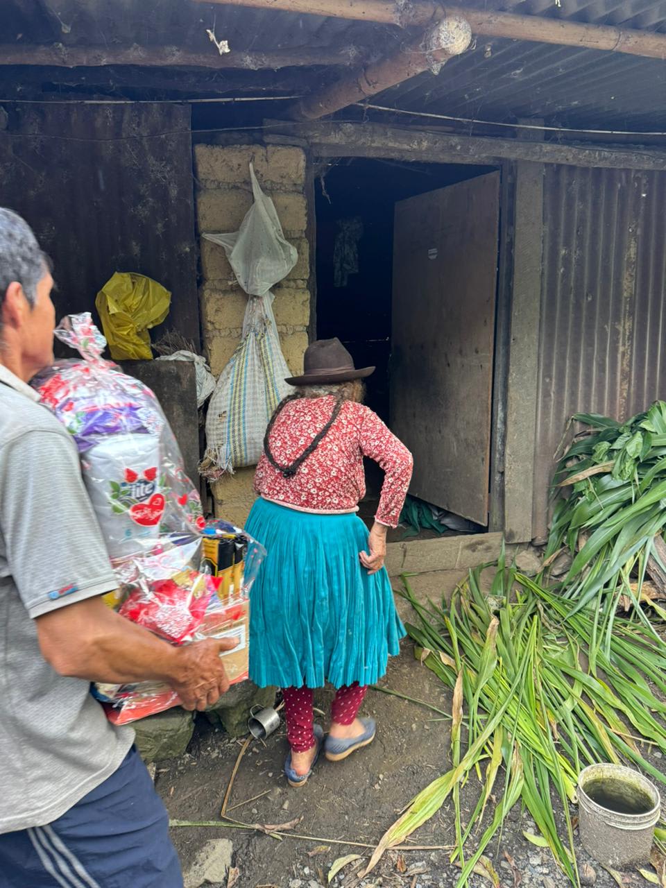 A guide carrying supplies while an elder walks toward her home