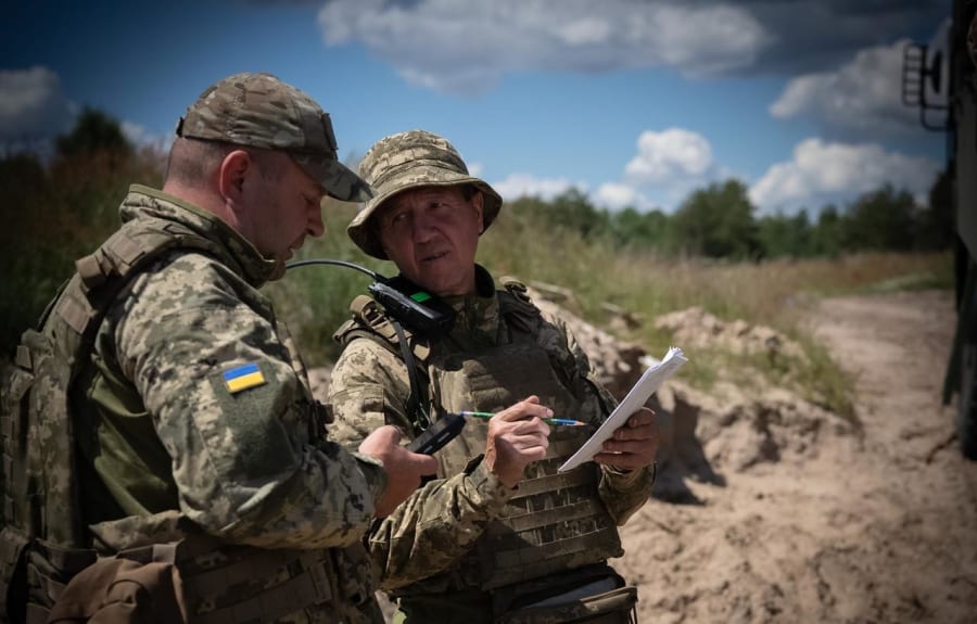 Двоє військових обговорюють документи на піщаній позиції