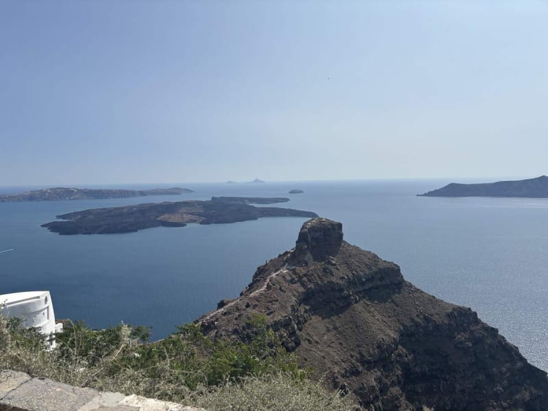 A white chapel perched on the caldera rim near Profitis Ilias, Thirasia across the water