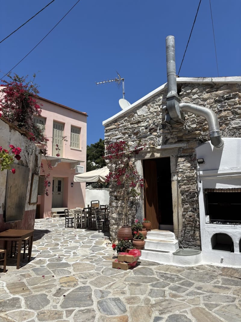 The square in the mountain village at midday. Empty tables, hot sun, and a kitchen that smelled like something was already roasting.
