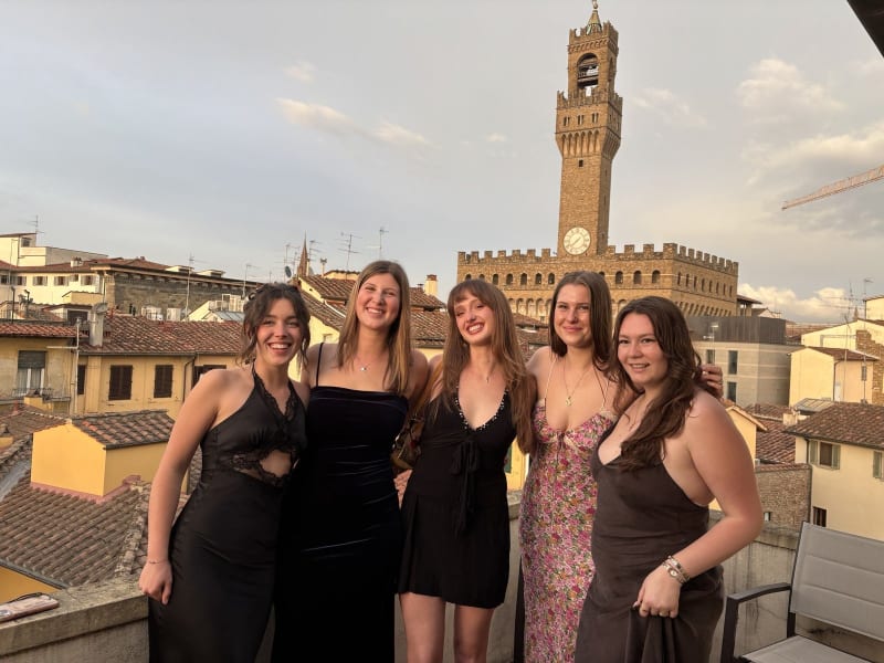 Julia and her study abroad friends dressed for their formal closing dinner on our rooftop terrace. Fred Again on the speaker, prosecco in hand, Palazzo Vecchio in the background.