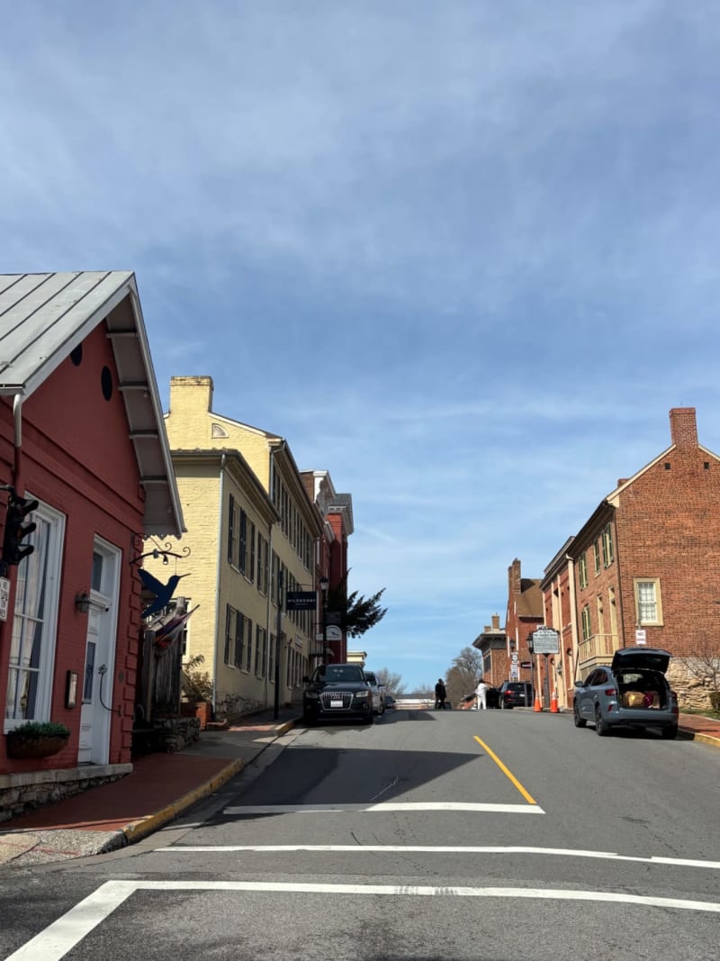Historic brick and colonial buildings line a charming street in a New England town under blue skies.