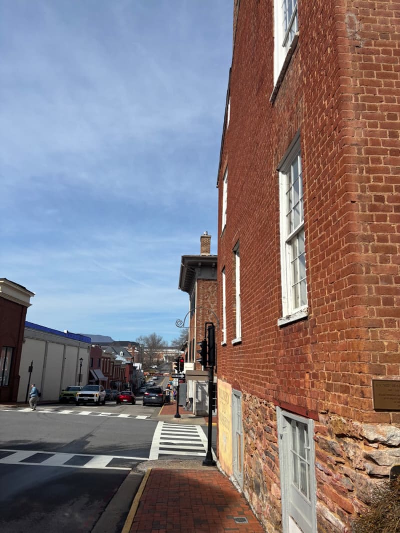 # Alt Text
A brick building with white-trimmed windows overlooks a charming downtown street with crosswalk and parked cars.