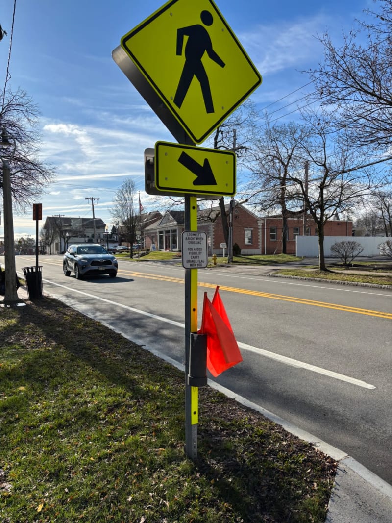 Pedestrian crossing warning sign with directional arrow on a residential street.