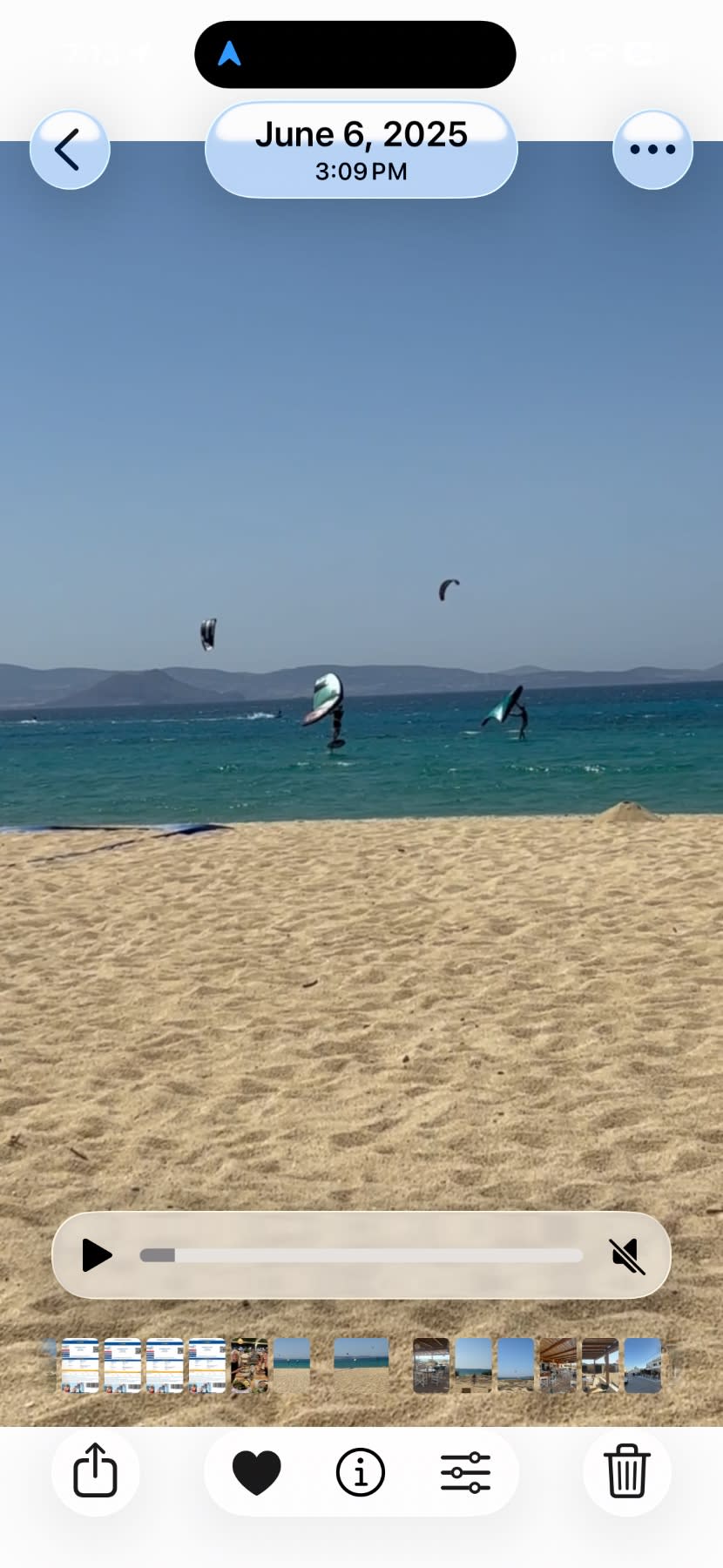 Kitesurfers perform tricks in turquoise water off a sandy beach under clear skies.